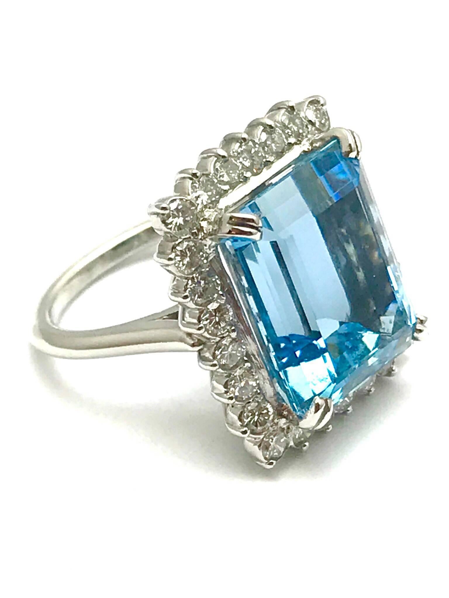 A 12.16 carat emerald cut aquamarine and diamond platinum ring.  The aquamarines is set with four double prongs sitting above a single row of 26 round brilliant diamonds that have a total weight of 1.10 carats, and are graded as F-G color, VS
