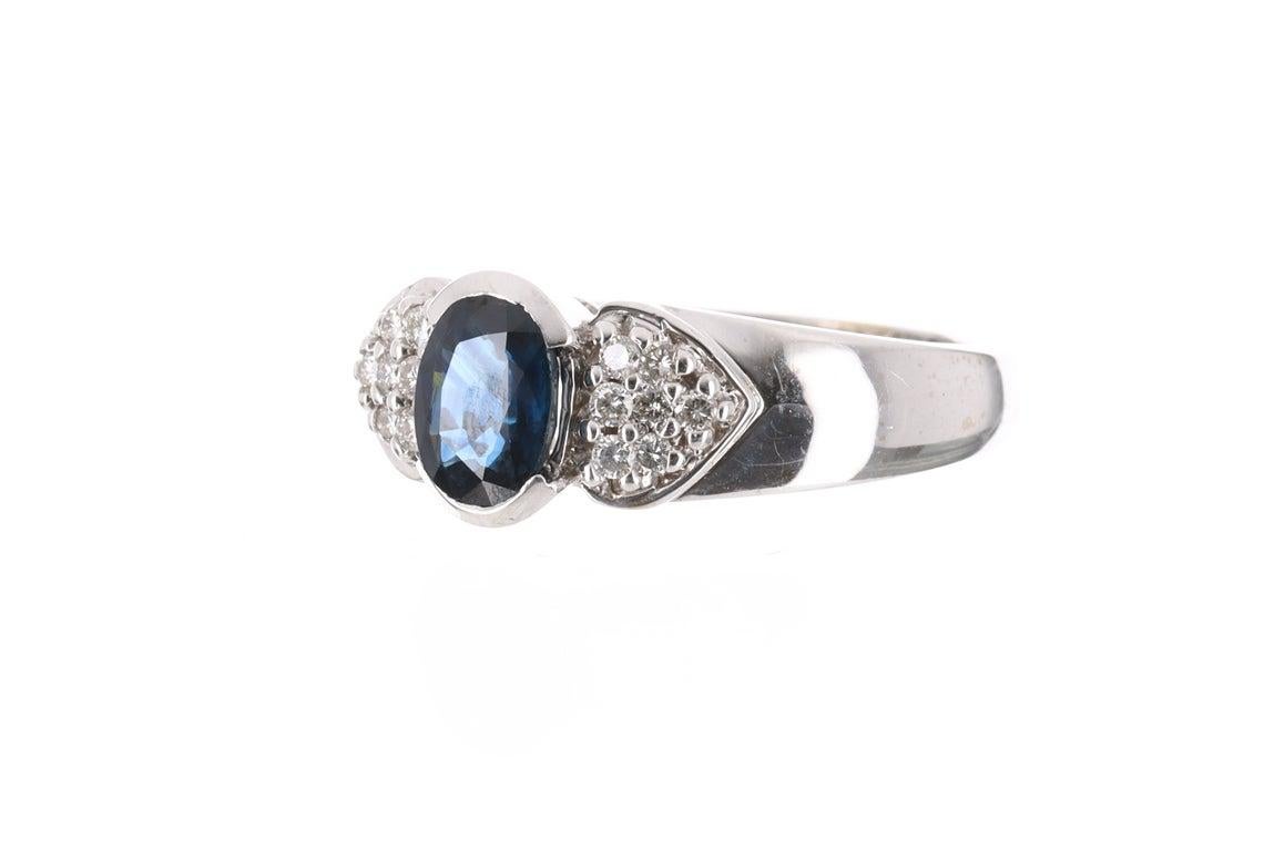 Displayed is an intense dark sapphire and diamond pave ring that is full of life and sparkle from any view. 14 fully faceted round cut diamonds are pave set on either side of the sapphire in a romantic setting. Created in solid 14 karat gold, this