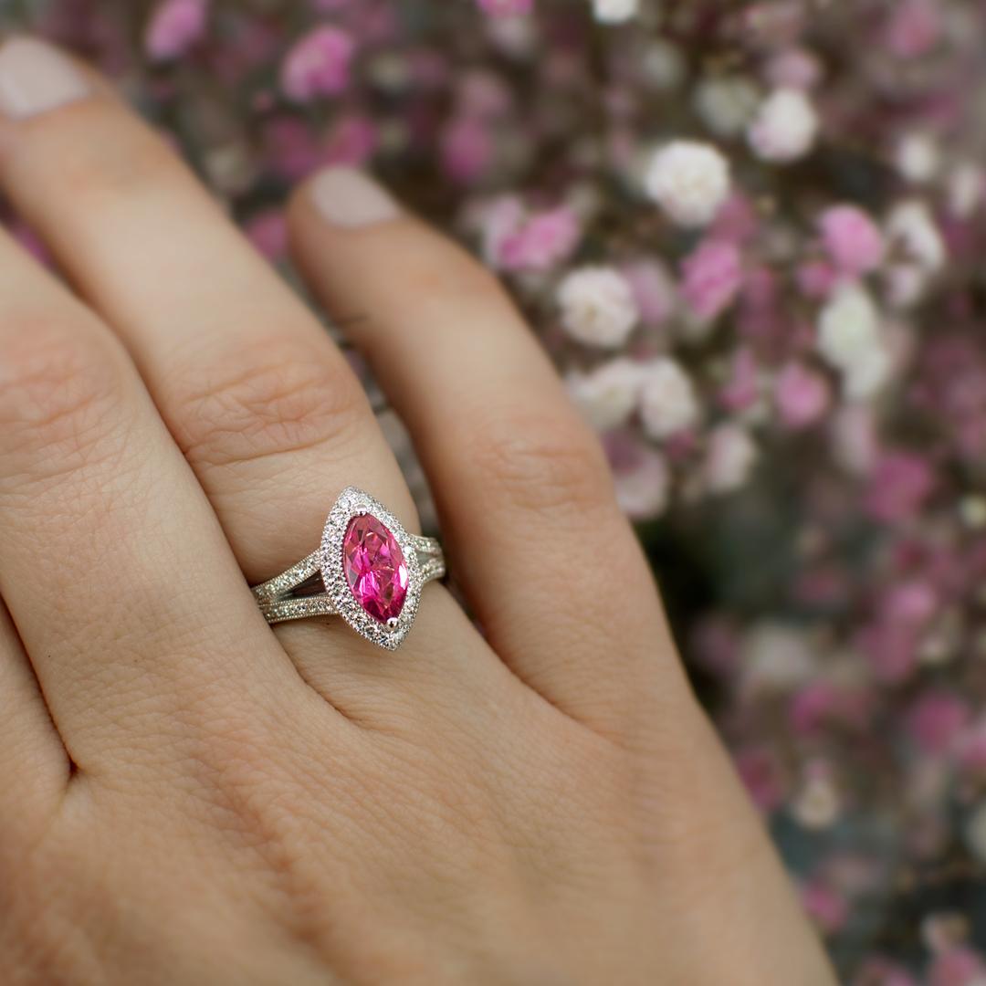 A stunning cluster engagement ring featuring a spectacular and vibrant marquise-cut pink tourmaline surrounded by milgrained round brilliant diamonds and a beautiful milgrained diamond split band. The marquise Pink tourmaline weighs 1.22 carat and