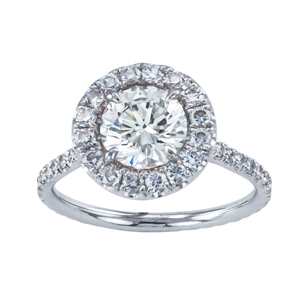 1.22 carats diamond solitaire and white gold engagement ring.  Centering upon a round brilliant-cut diamond weighing approximately 1.22 carats, approximately H – I color and VS2 clarity, within a conforming border of smaller, similarly cut diamonds