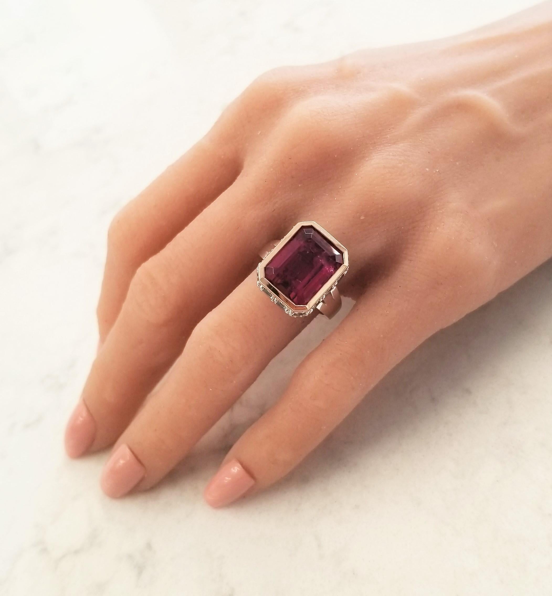 This ring raises the design bar! A 12.22 carat deep purplish-pink rubellite tourmaline is bezel set in the center in a rich rose gold and measures 15x11mm. The gem source is Brazil; its saturation is vivid; its transparency and luster are excellent.