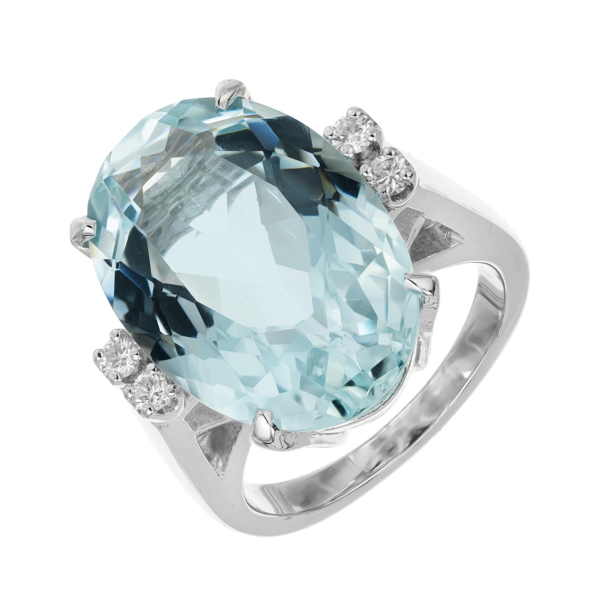 This stunning 1950's oval aquamarine has a total carat weight of 12.27cts. Perfectly mounted in a 14k white gold cocktail setting. On each side of the aqua are 2 round brilliant cut accent diamonds. The mid-century design of this cocktail ring makes