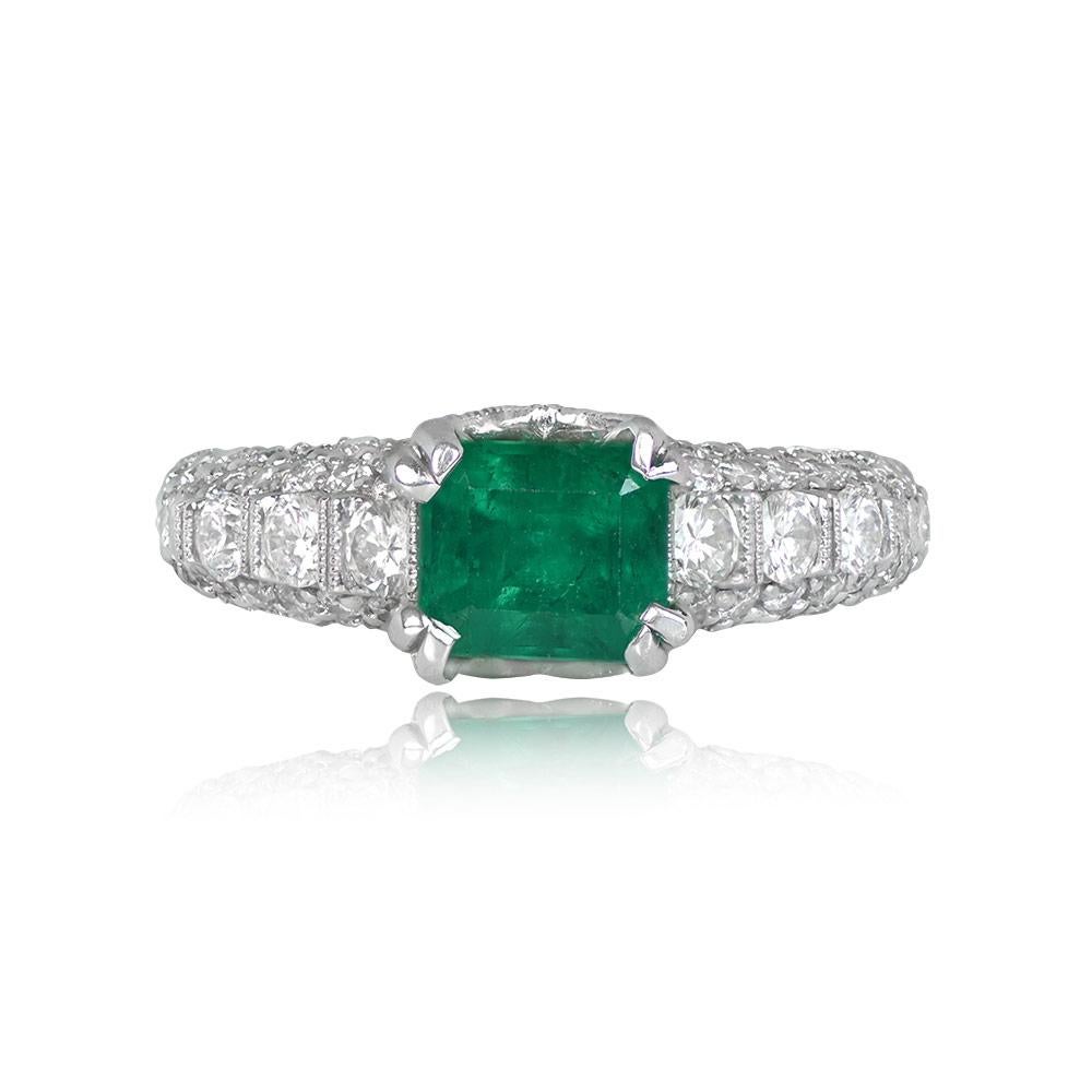 This exquisite ring highlights a 1.22-carat emerald-cut emerald, securely set in prongs and adorned with round brilliant-cut diamonds on each shoulder. The total diamond weight of the accents is 1.48 carats. The ring is elegantly crafted in 18k