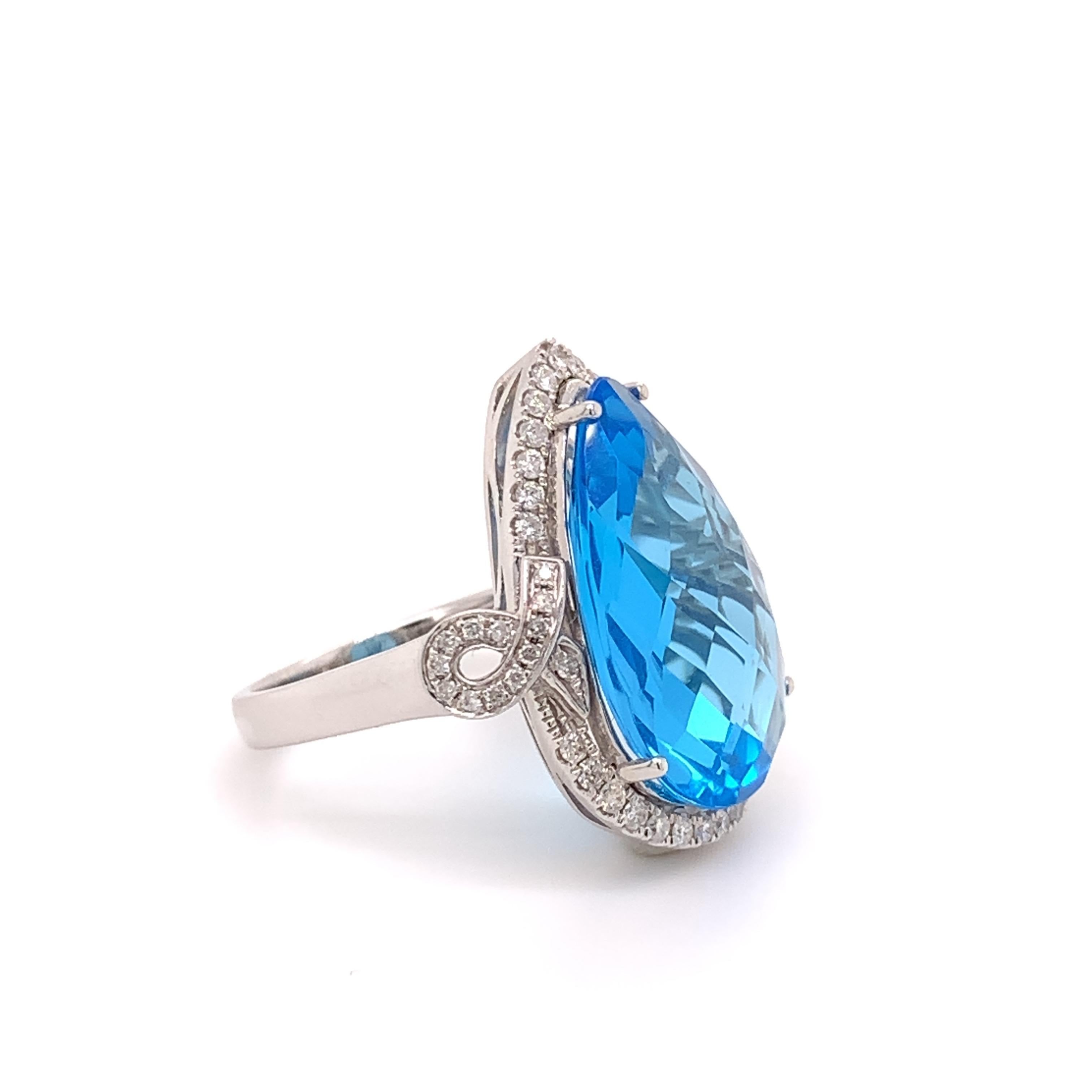 Glamorous topaz diamond cocktail ring. Lively sky blue, high brilliance with checkered-board cut, pear faceted 12.36 carats topaz mounted in high profile open basket, accented with round brilliant cut diamonds. Handcrafted design set in high