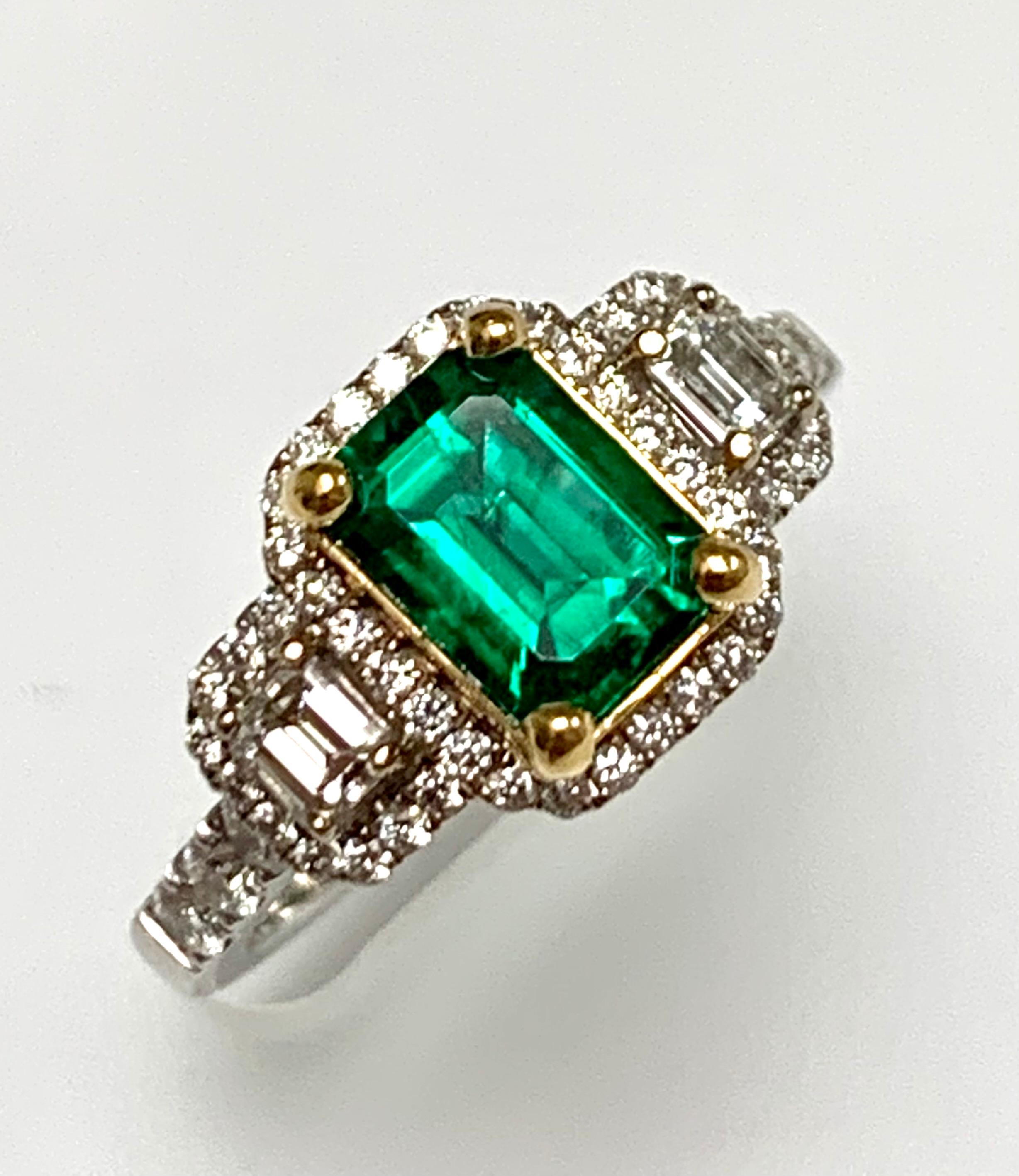 1.24 Carat emerald cut  Zambian emerald set in 18k white ring  / yellow gold basket , surrounded with  round diamonds around emerald  and pair of emerald cut diamonds in three stone style as well as diamonds set half way on the shank.