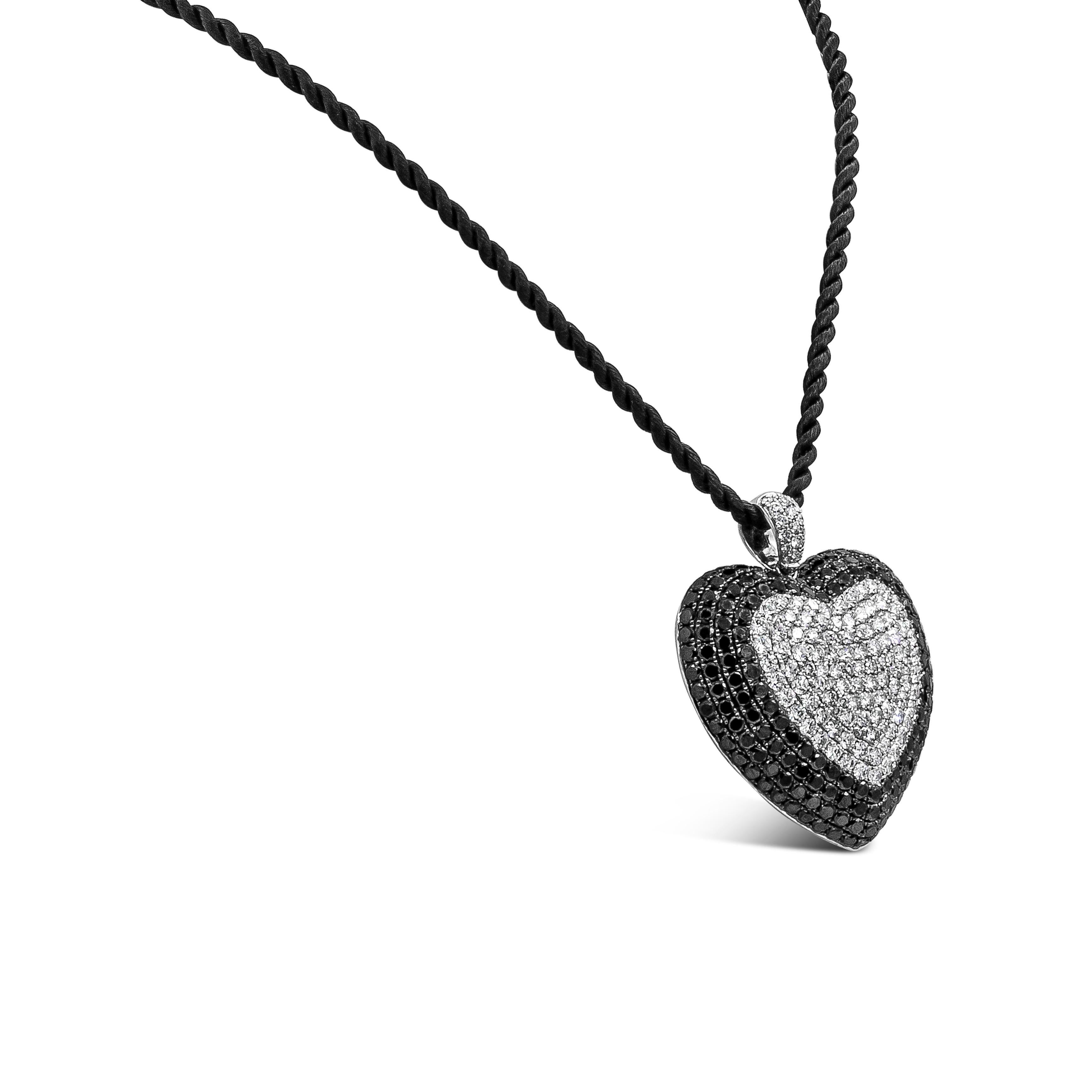 An important and beautiful pendant necklace showcasing a cluster of round brilliant black and white diamonds set in a domed heart shape pendant made in 18k white gold. Diamonds weigh 12.40 carats total. Suspended on a 18 inch adjustable rope. Length