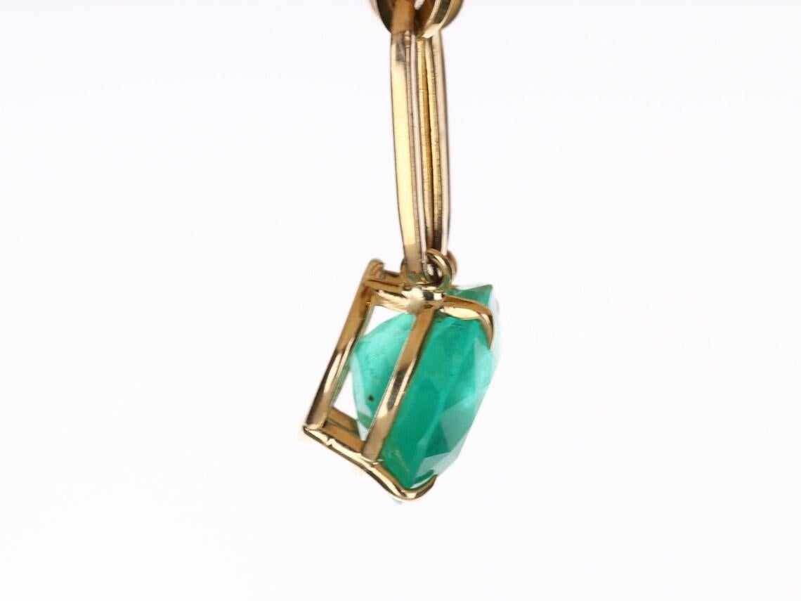 Featured here is a 12.41-carat stunning, East to West emerald necklace in 14K yellow gold. Displayed in the center is a medium green emerald with very good eye clarity for its large size, accented by a simple prong setting, allowing for the emerald