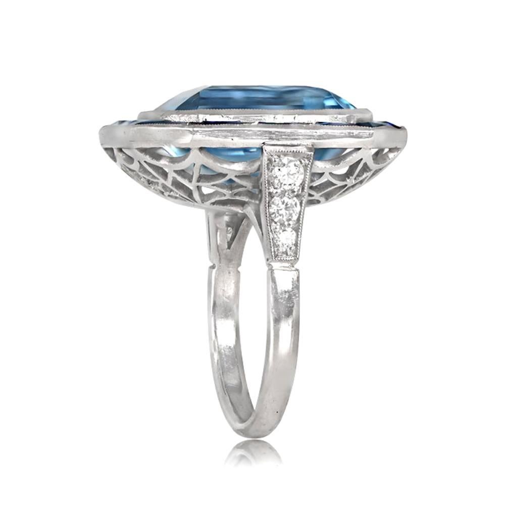 This platinum ring is a sight to behold, featuring a stunning 12.46-carat aquamarine, bezel-set and encircled by a halo of calibrated French cut sapphires weighing 5.20 carats. The ring's shoulders are adorned with small round brilliant cut diamonds