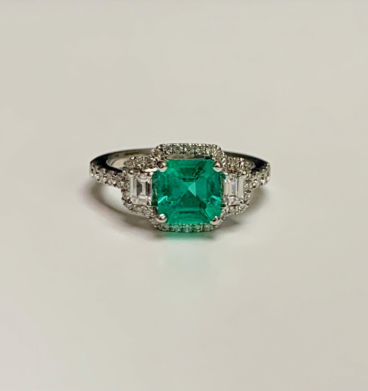 1.25 Karat kolumbianischer Smaragd im Asscher-Schliff in einem 18-kW-Ring im Dreistein-Stil, [Diamanten im Pave-Stil rundherum und auf halber Höhe des Schafts.