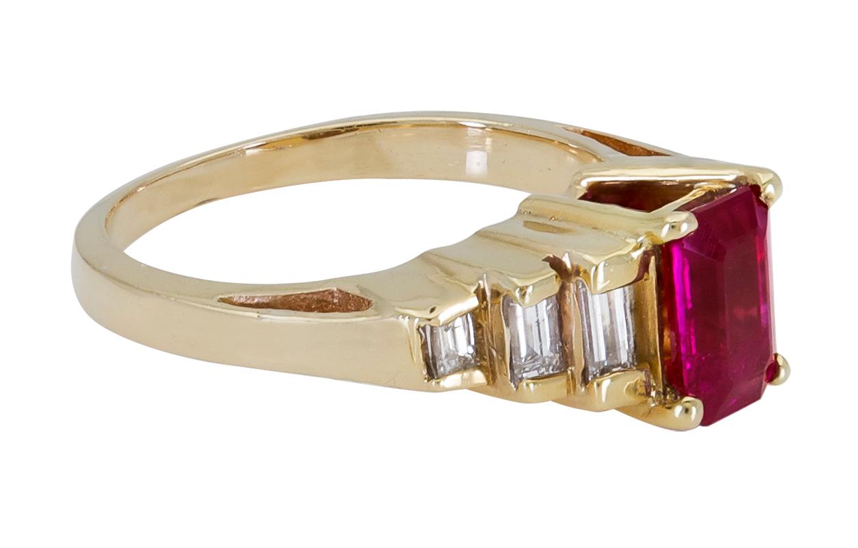 A magnificent engagement ring showcasing a 1.25 carat emerald cut red ruby. Flanking the center gemstone are three graduating baguette diamonds on either side. Made in 18k yellow gold. 
Ruby weighs 1.25 carats.
Diamonds weigh 0.20 carats total.
Size