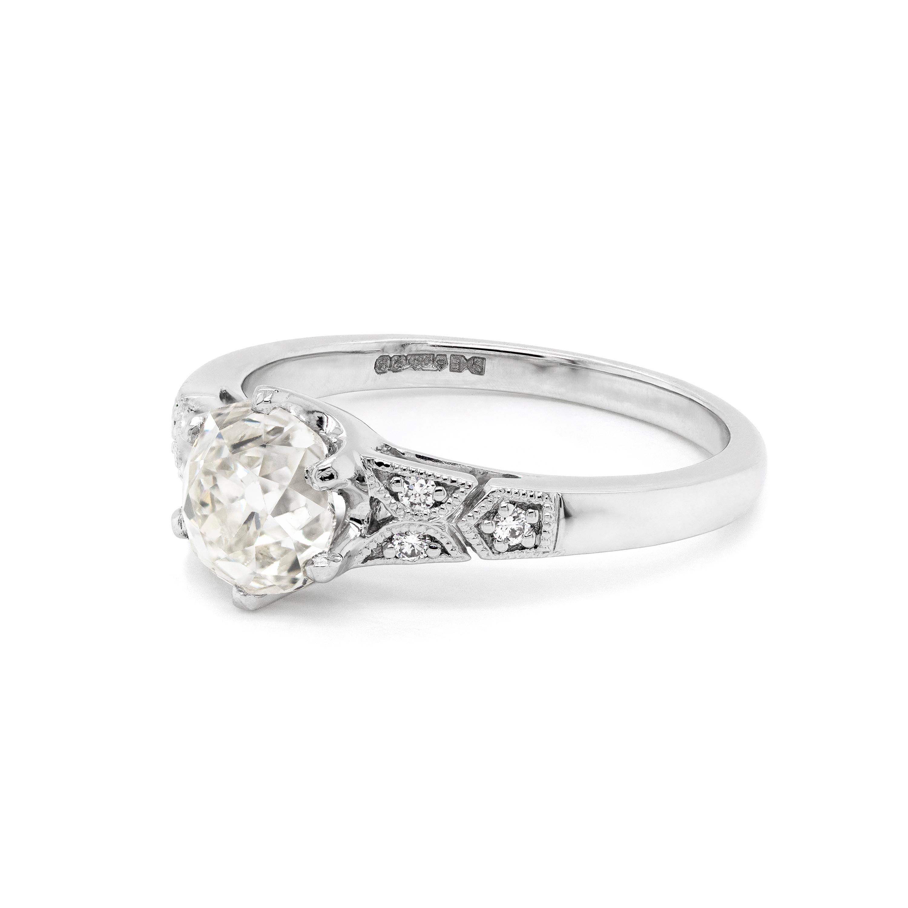 Dieser wunderschöne Verlobungsring im Art-Déco-Stil enthält einen Diamanten im Altschliff von 1,25 Karat in einer Fassung mit sechs Krallen und offener Rückseite. Der zentrale Diamant wird von drei runden Diamanten im Brillantschliff auf beiden