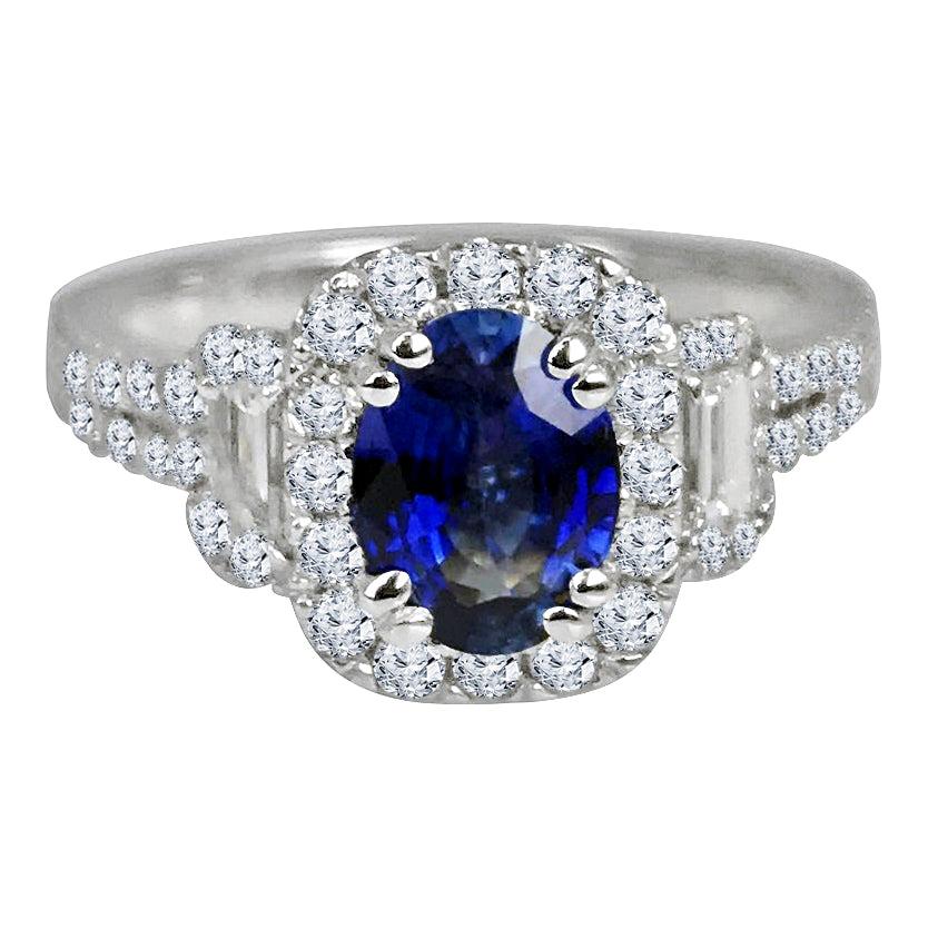 This stunning ring showcases a dazzling 1.25 carat oval-cut sapphire at its core, embraced by a halo of round natural diamonds and complemented by two elegant baguette natural diamonds. Additional diamonds gracefully descend along the split shank,