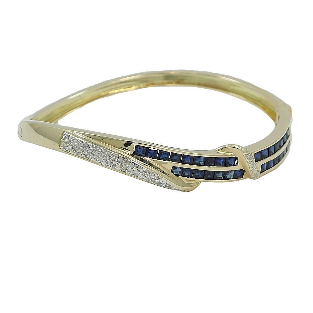 14K Yellow Gold Sapphire and Diamond Bangle Bracelet. The Twenty Four (24) Diamonds Weigh Approximately 0.35 Carats Total Weight and The Twenty Nine (29) Sapphires Weigh Approximately 1.25 Carats Total Weight. It Measures 2.5 Inches In Width and