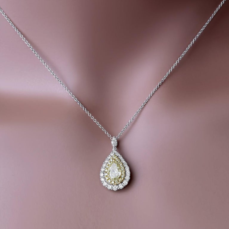 This pendant has a GIA certified 0.52 carat yellow pear shape center, surrounded by a halo of round yellow diamonds, to give the impression of a larger center. All this is surrounded by an additional halo of round white diamonds for a classic look.