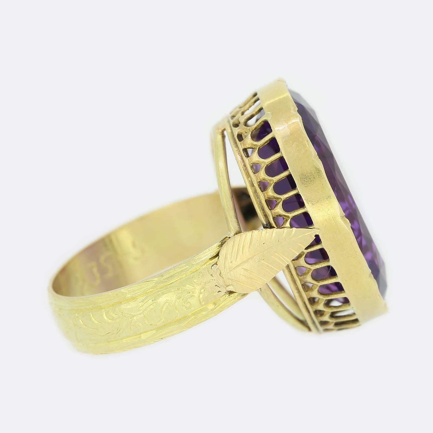 This is an antique amethyst solitaire ring. The ring features a large oval cut amethyst which has been rubover set in 18ct yellow gold with an engraved band and leaf design shoulders. The ring started life as a Victorian pendant but has been