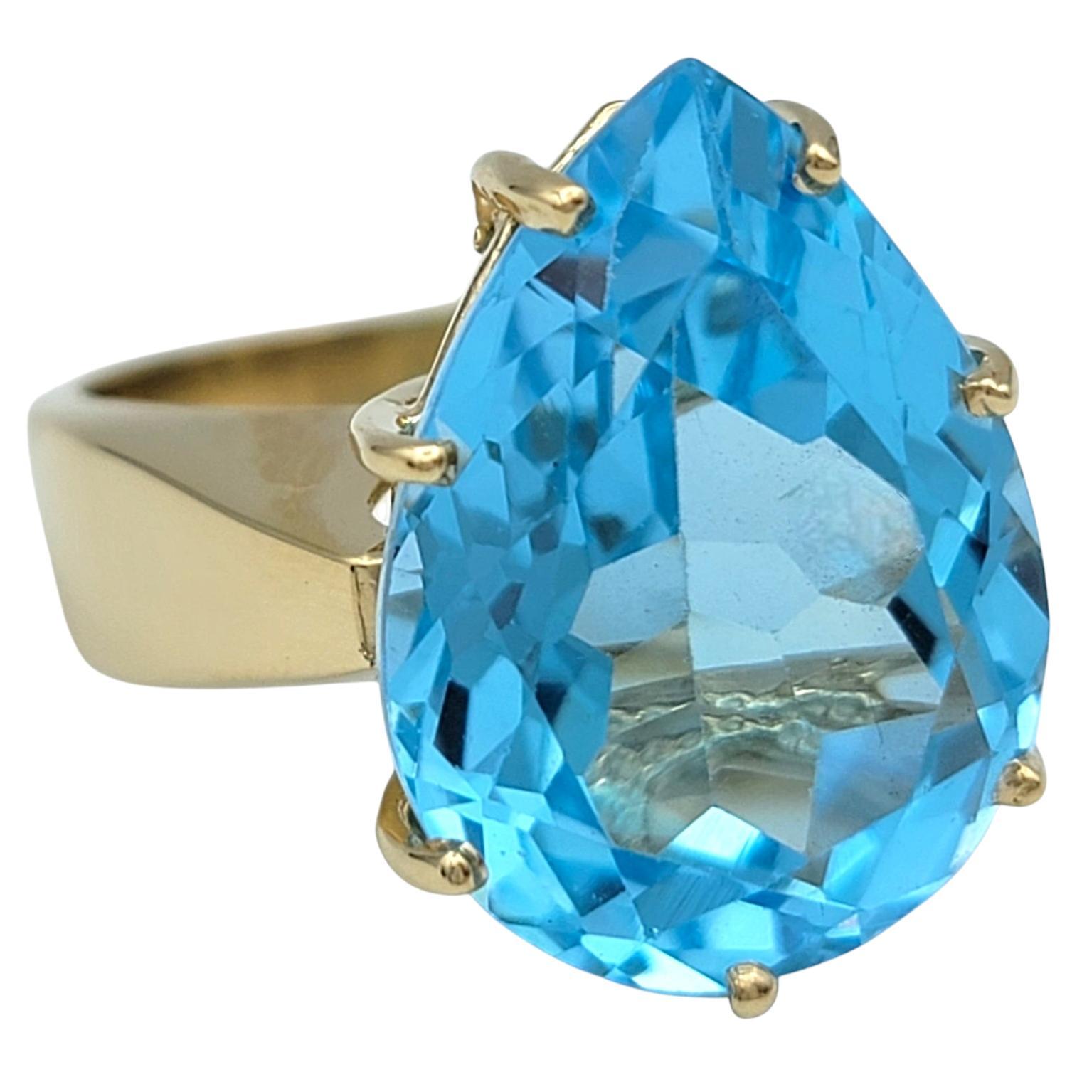 Ring Size: 7

Indulge in the timeless allure of this exquisite 14 karat yellow gold ring, designed to captivate with its bold elegance and striking centerpiece. At its heart, a breathtaking 12.50 carat pear-cut blue topaz radiates a vivid, oceanic