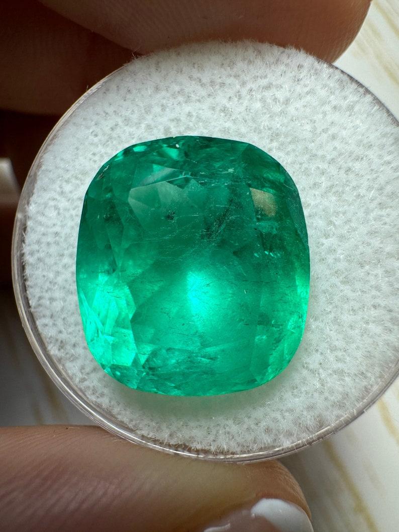 Stone: Emerald
Weight: 12.50-carats
Shape: Cushion Cut
Clarity: Transparent
Luster: Very Good
Color: Medium Intense Green
Measurements: 15.22mm x 13.53mm x 10.02mm
Geographic Origin: Colombia
Treatment: Natural, Oiling

Comments: Due to their growth