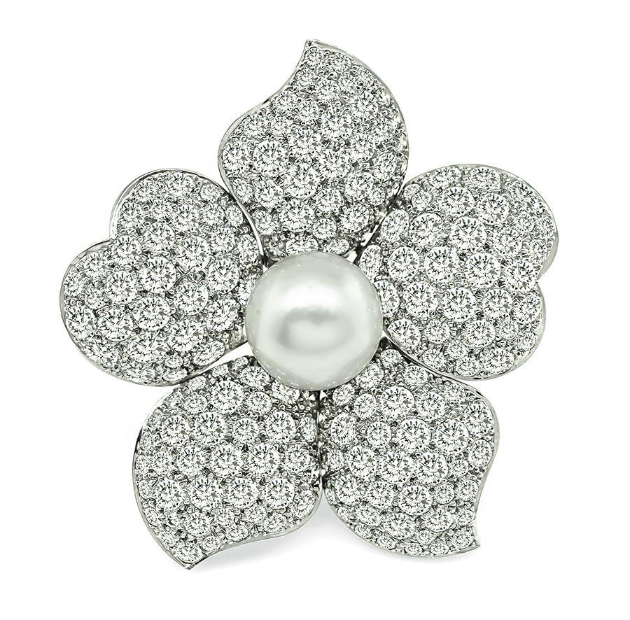 This is an elegant 18k white gold flower pin. The pin is set with sparkling round cut diamonds that weigh approximately 12.50ct. The color of these diamonds is E-F with VS1 clarity. The diamonds are accentuated by lovely round pearl. The pin