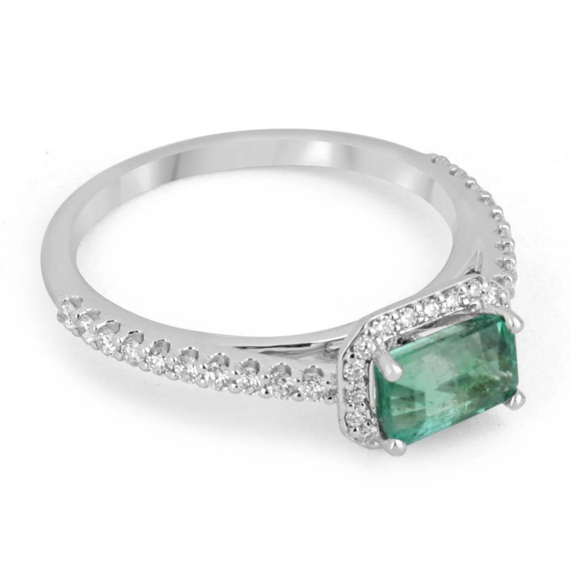 A stunning emerald and diamond engagement ring. The center gemstone features a 0.95-carat, natural Zambian emerald with great qualities. A medium green color, very good eye clarity and luster; set east to west. A diamond halo surrounds the gorgeous