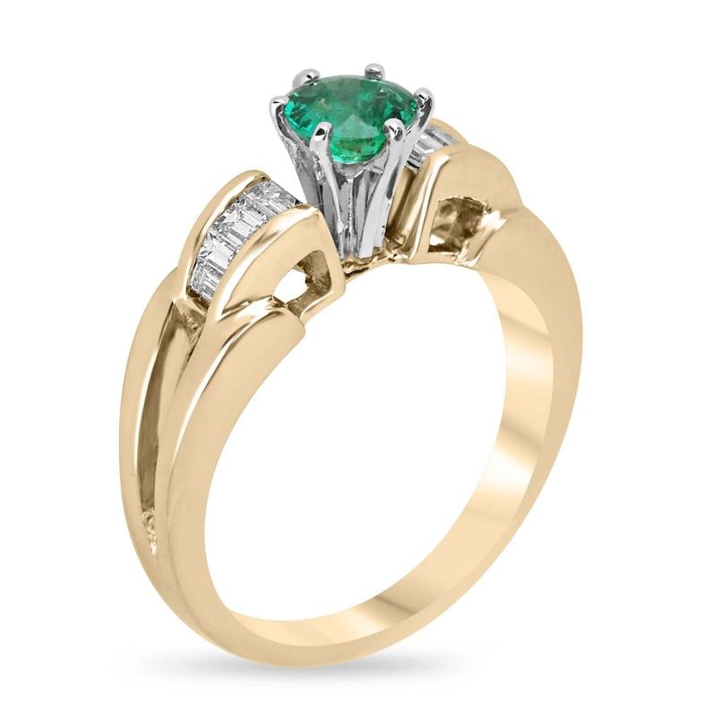 Feiern Sie Ihre Liebe mit unserem bezaubernden Verlobungsring mit Smaragd und Diamanten. Der schillernde Smaragd im Rundschliff von 3/4 Karat ist von exquisiter Qualität, strahlt einen satten Grünton aus und besticht durch seine halbtransparente