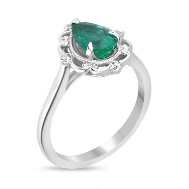 This stunning emerald and diamond accent ring features a breathtaking 1.20-carat pear-cut emerald with a rich dark green hue and semi-transparent clarity, set in an elegant three-prong setting. Petite round-cut diamonds accentuate the emerald's