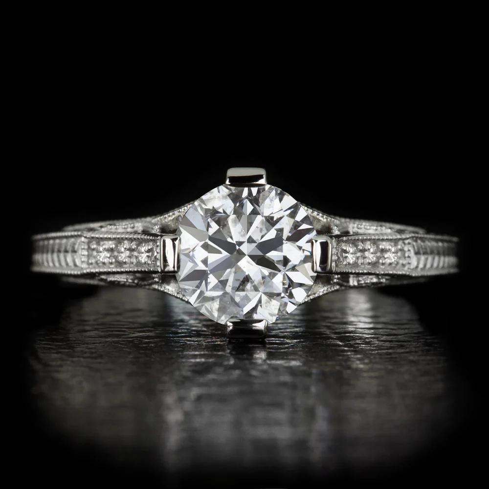 engagement ring’s classic design is crowned by a stunning round brilliant cut diamond. The bright white and vibrant 1.26ct diamond displays dazzlingly bright sparkle and vivid fire. The 14k white gold setting is stately in design, featuring romantic