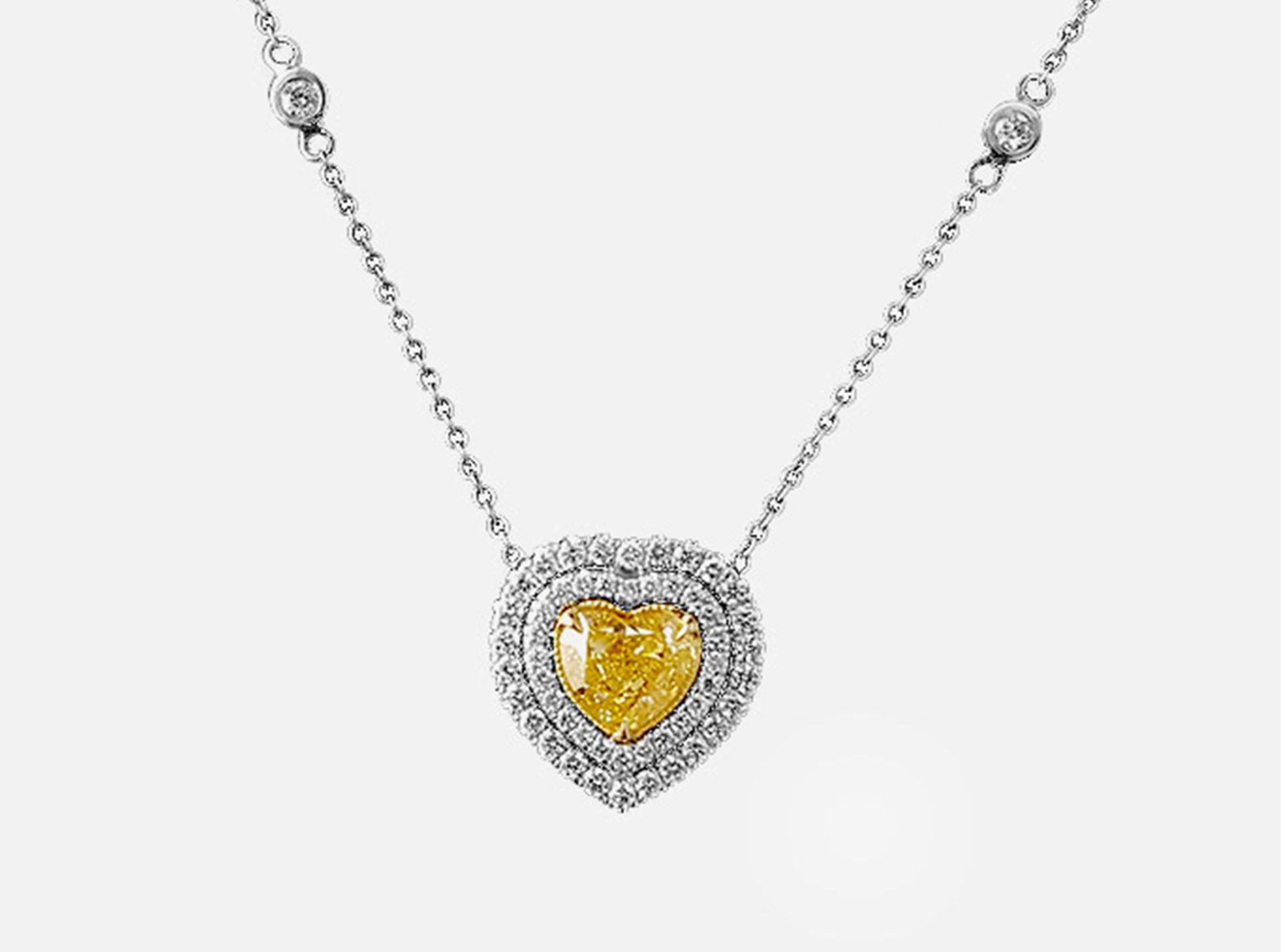 Introducing a stunning double Halo Pendant Necklace featuring a centerpiece of a GIA-certified 1.26 Carat Heart-shaped Fancy Yellow Diamond. This timeless design highlights the elegance of the central stone, enhanced by 56 surrounding round-cut