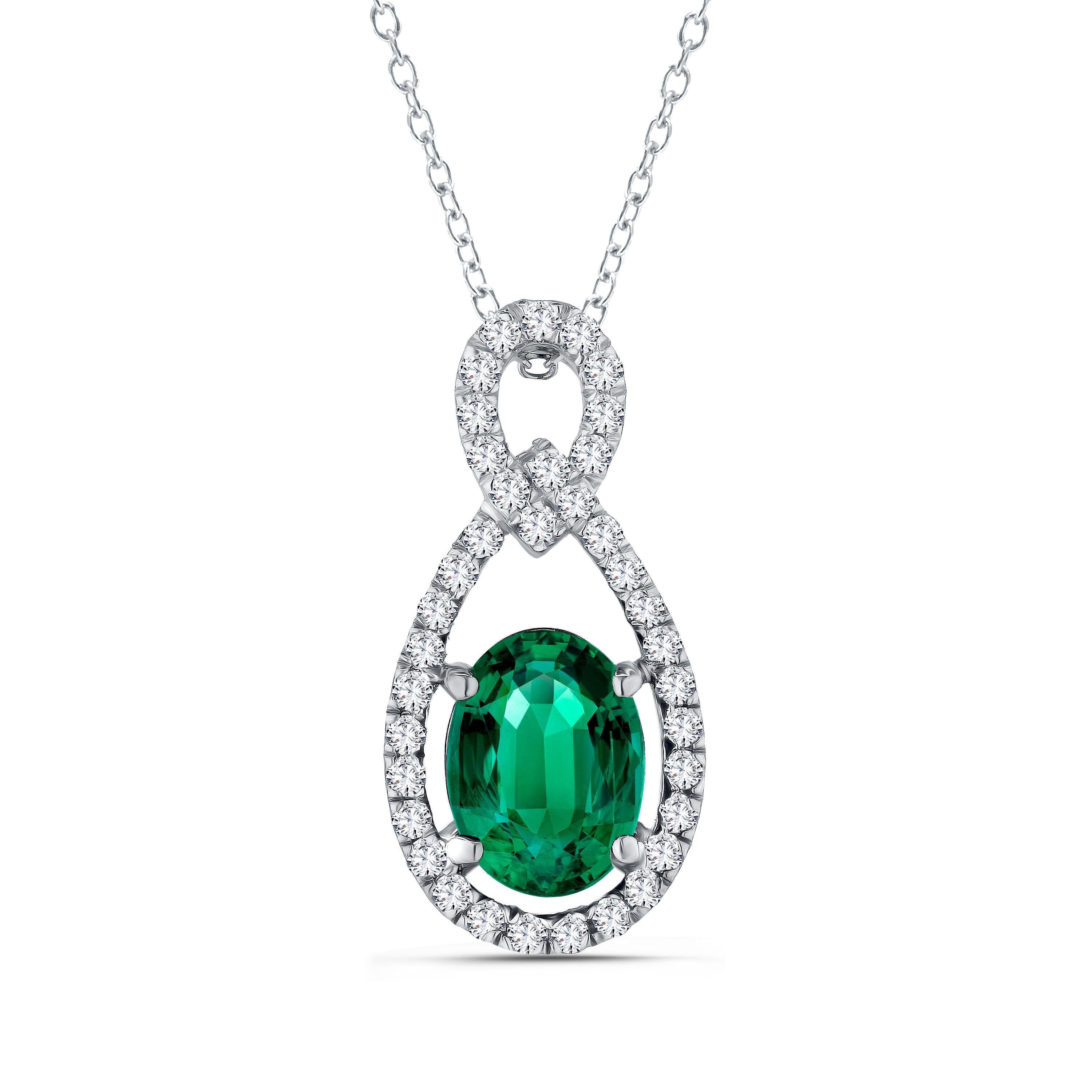 This beautiful pendant has a 1.26 carat oval cut emerald center, inside a halo of round white diamonds, with additional round diamonds on the bail (total diamond weight 0.22 carats). The setting is in 18k White Gold, with 18k Yellow Gold surrounding