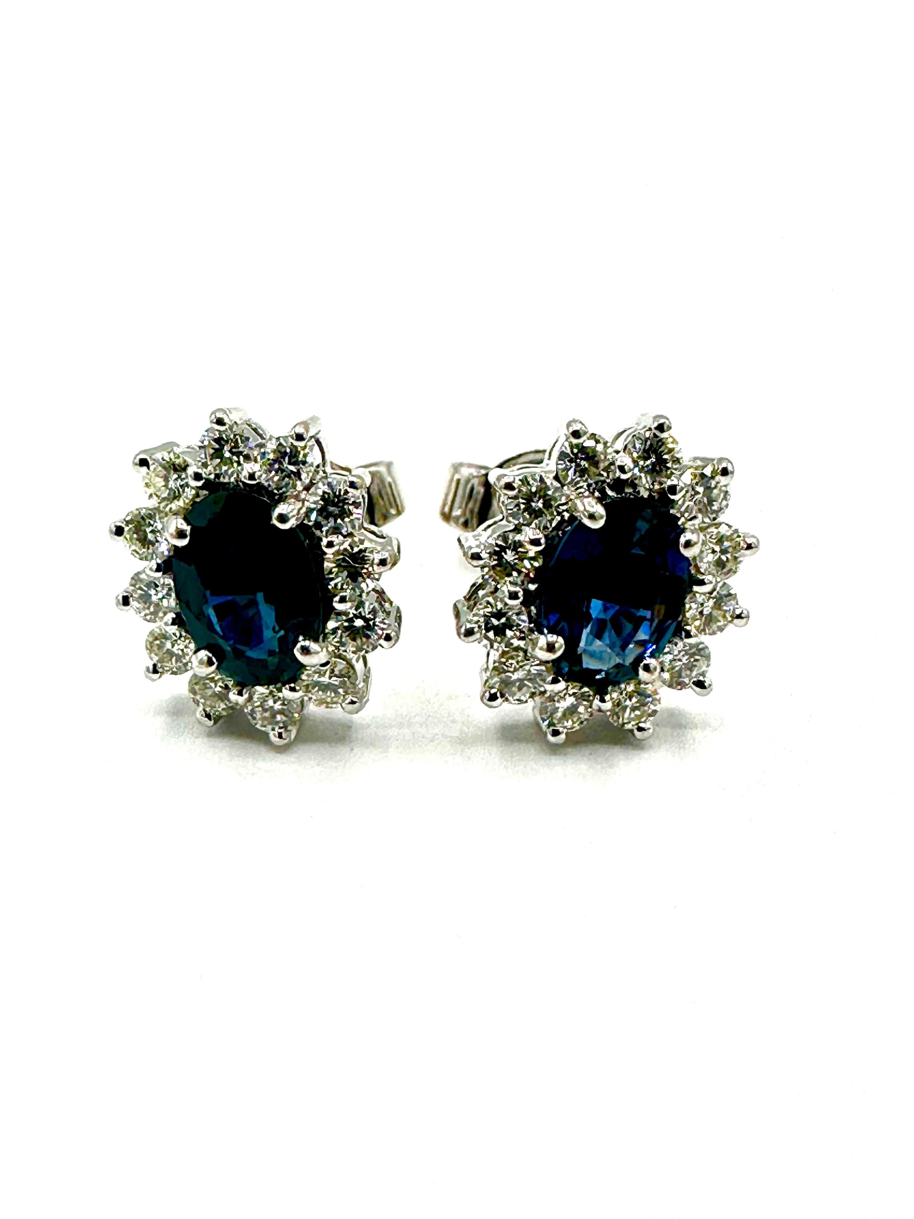 Simple and straight forward stud earrings!  These oval Sapphires are set in four prongs, surrounded by a single row of round brilliant Diamonds in 18K white gold, with a simple post back.  The two Sapphires have a total weight of 1.26 carats, and