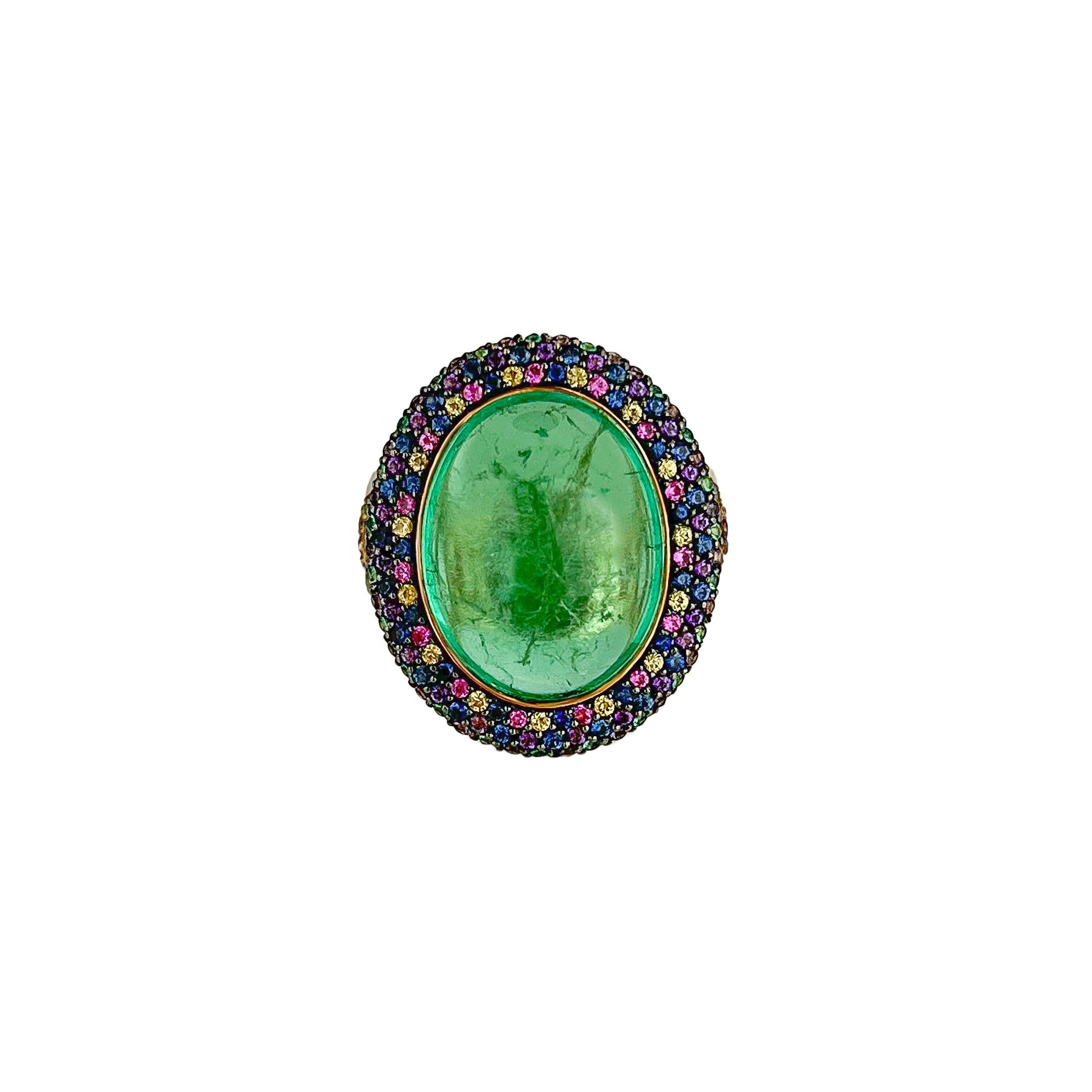 A classic shaped Emerald Cabochon was recreated into a modern piece with this 18k yellow gold ring. The 12.62 centre stone is decorated with a halo of pave’d Emeralds, Pink, Purple and Violet Sapphires. A chevron pattern of pave’d stones also