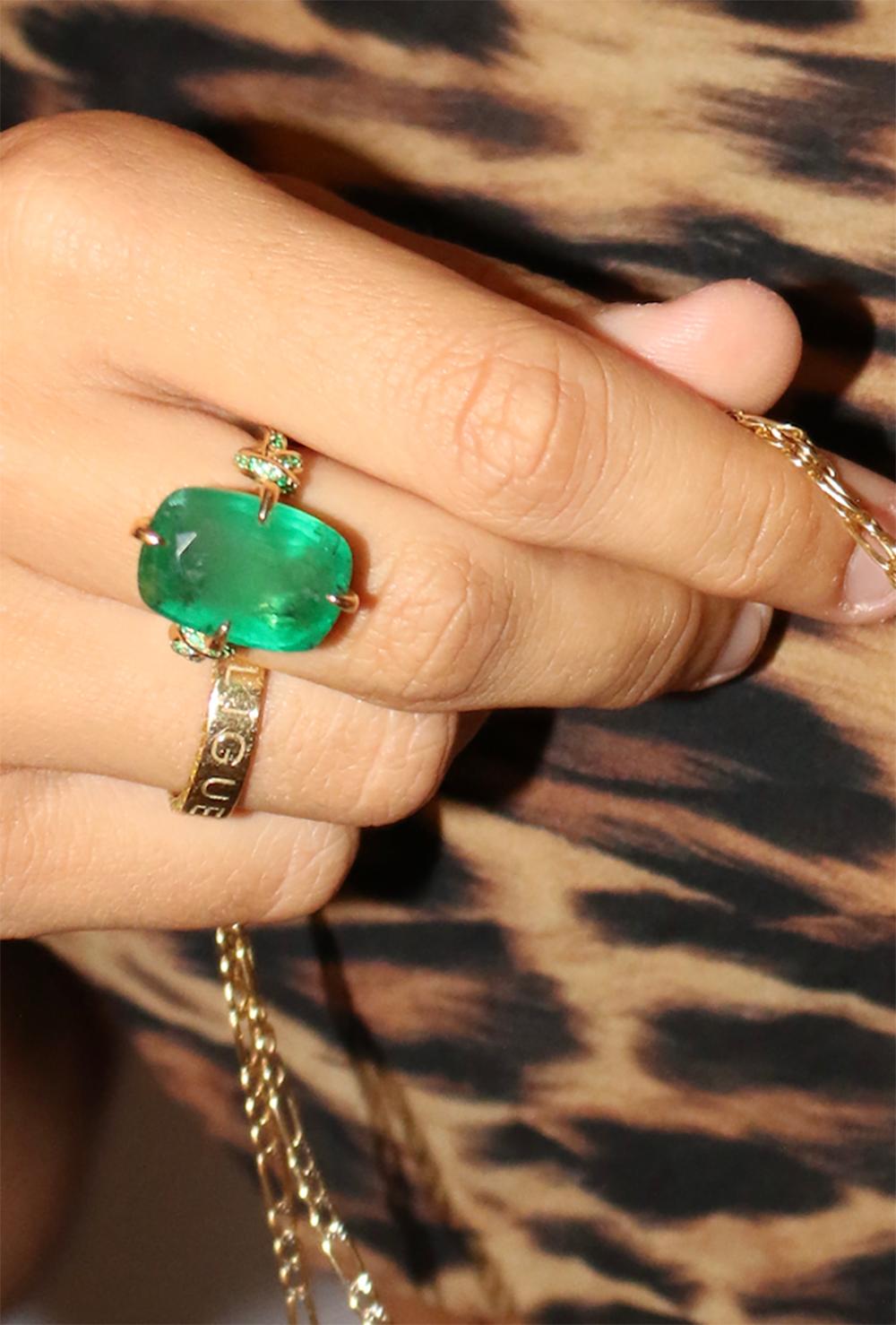 Glamorously bold and unabashedly seductive. This showstopper ring features an intense natural Emerald poised between sharp eagle style talons and embraced by powerful golden, emerald encrusted ropes, converging to two knots on either side of the