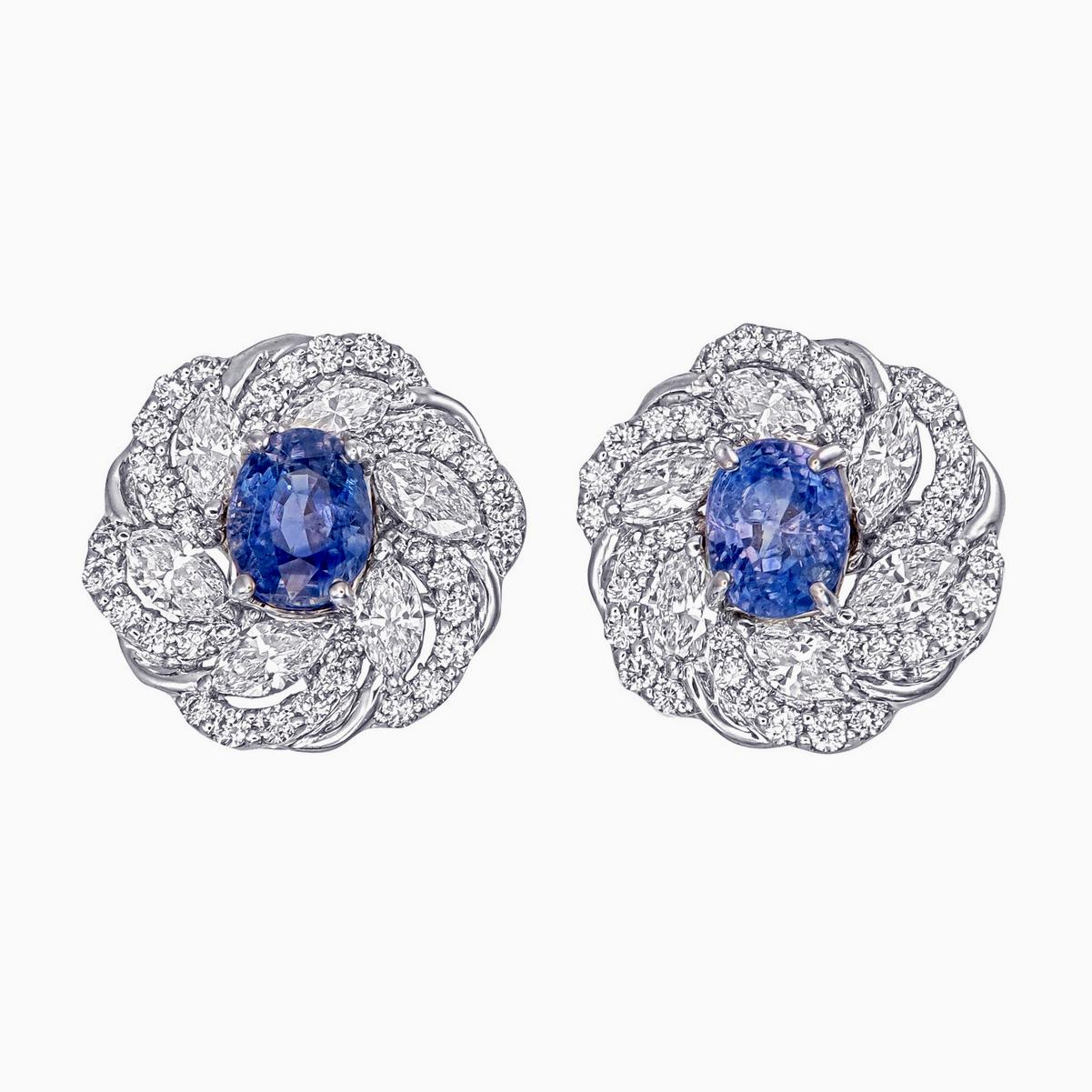 Ein elegantes Paar  Die Rubin- und Diamantohrringe von Rewa Jewels sind aus 18 Karat Weißgold gefertigt.

Das Mittelstück ist aus natürlichem, unbehandeltem  Blauer Saphir in ovaler Form mit einem Gewicht von etwa 1,27 Karat. 

Die Ohrringe sind mit
