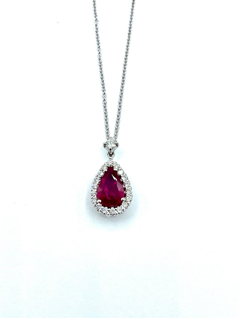 A stunning and vibrant pigeon blood red pear shaped Ruby!  The Ruby is set in four prongs, surrounded by a single row of round brilliant cut Diamonds, suspended from a single round brilliant cut Diamond bale, all in platinum.  The Ruby weighs 1.27