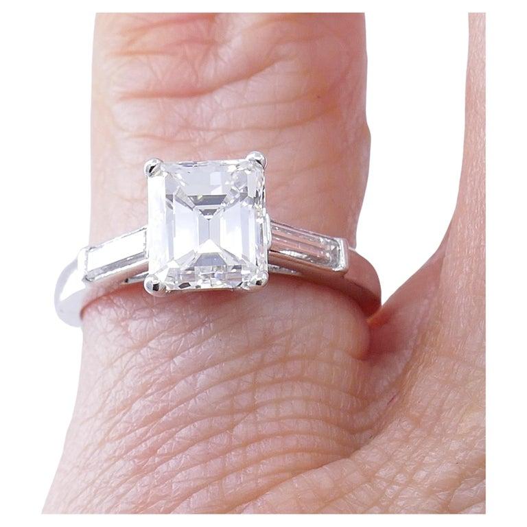 A diamond solitaire with accents and platinum ring of a classic design.
The ring’s center stone comes with a GIA Diamond Grading Report and has excellent characteristics (see picture 3). The emerald cut gem is four-prong set and flanked with two