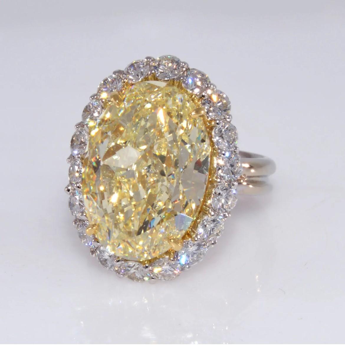 A gorgeous oval cut GIA certified 12.71 carat fancy light yellow diamond set in 18k white gold. This stunning halo setting has 18 beautiful white diamonds set in a handmade ring setting. Ring size is 6.5, and this ring is preowned.