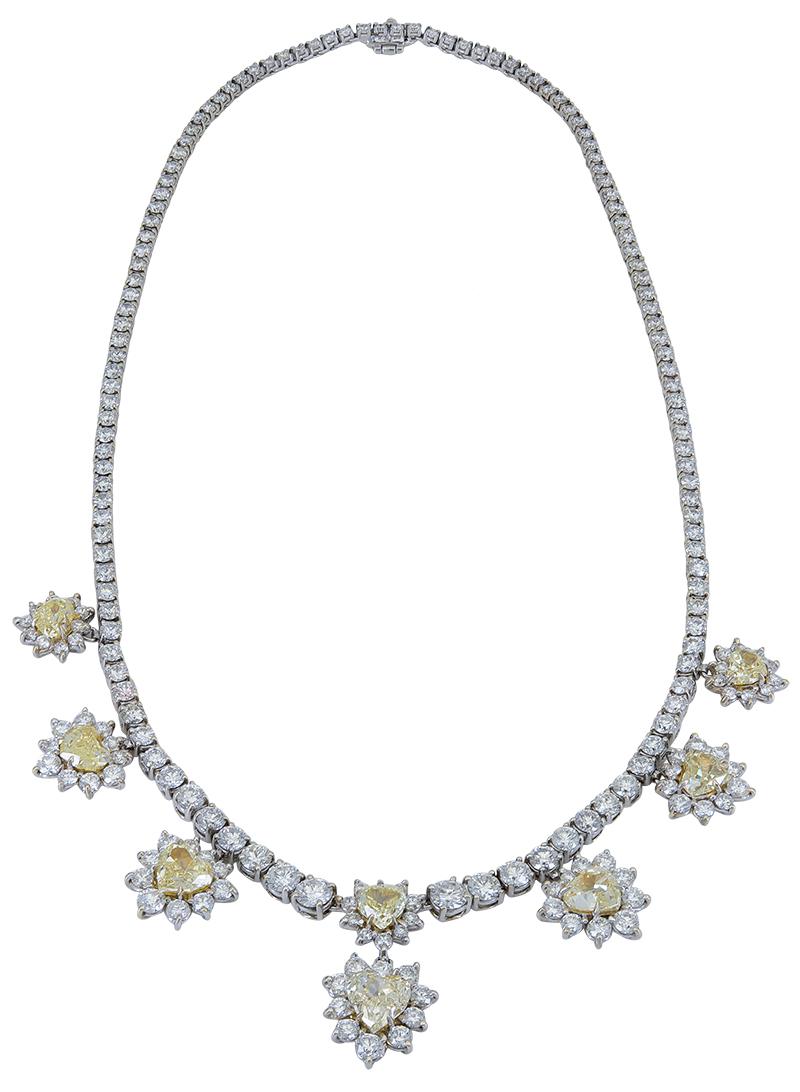 A stylish and important piece that would be the perfect center piece in a formal, or gala outfit. Features a brilliant diamond tennis necklace set with round diamonds, accented by seven heart shape yellow diamond halos that elegantly drop from the