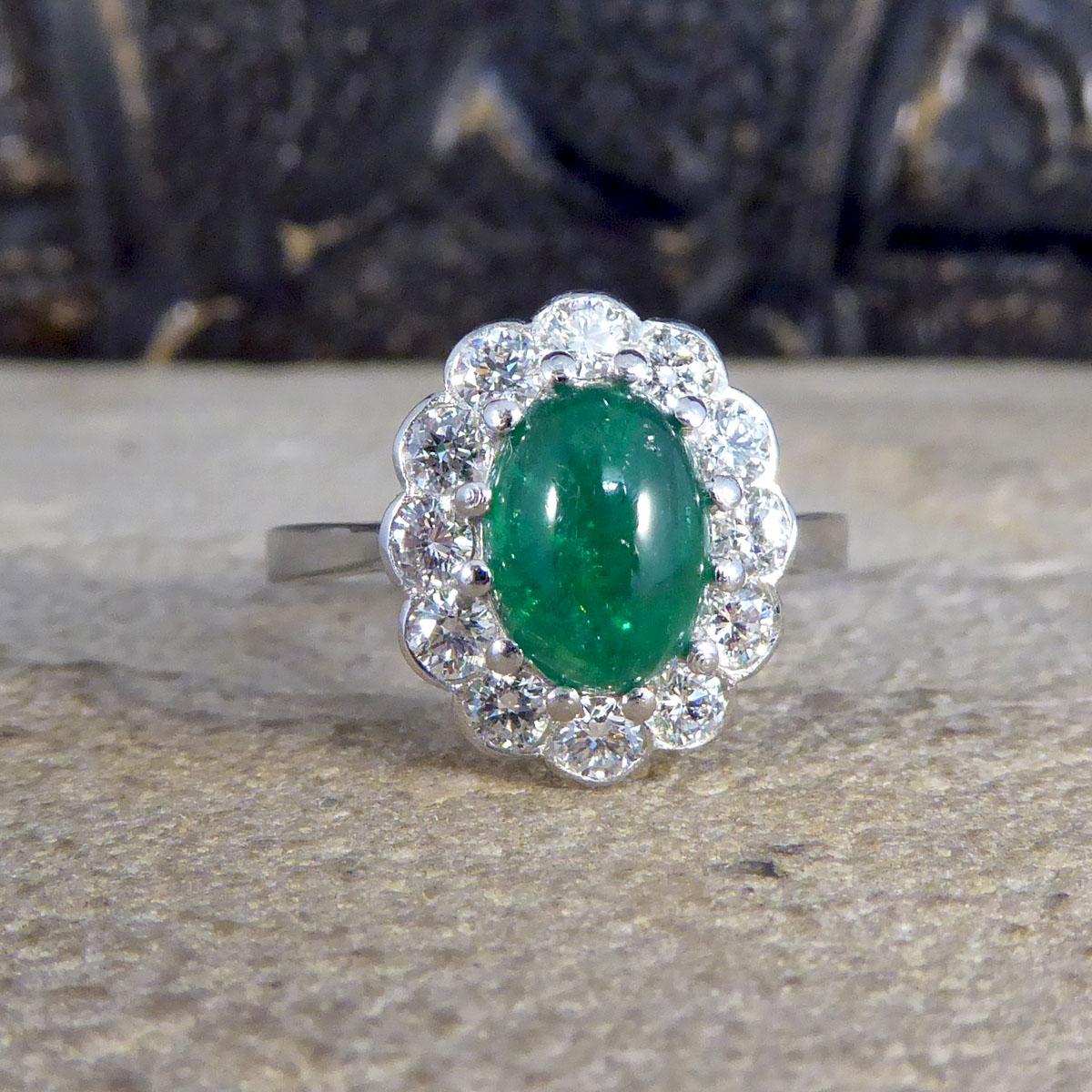 Featuring a vibrant green Cabochon Emerald weighing 1.27ct in a claw setting, this ring shows such quality through the gemstones and such bright colour that the Emerald has. The gorgeous contemporary ring is clustered with round cut diamonds
