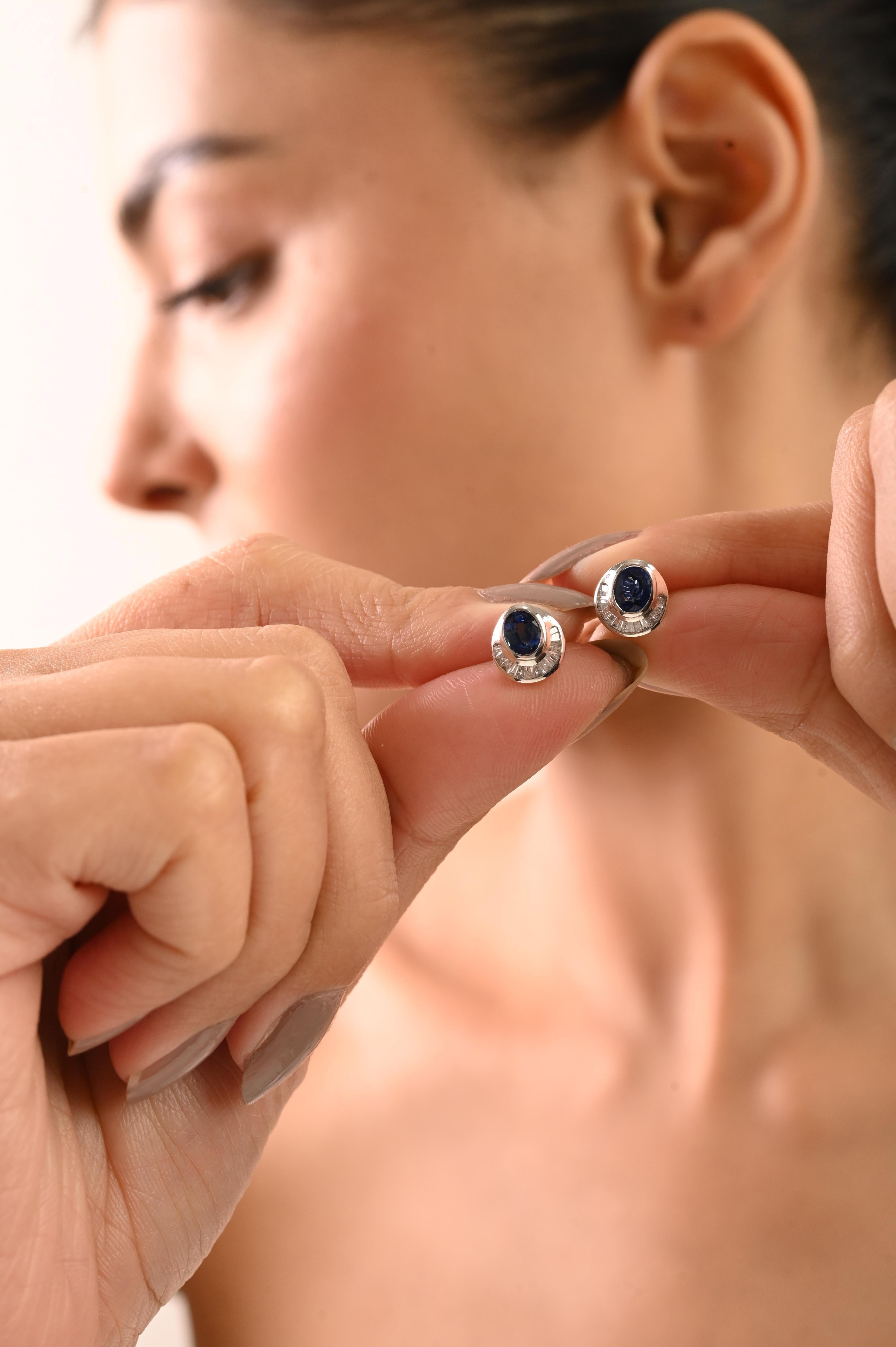 Ces élégantes boucles d'oreilles sont ornées de saphirs bleus naturels ovales de 1,27 carat, rehaussés de diamants baguettes effilés de 0,15 carat dans un design semi-halo. Les pierres précieuses sont solidement serties en lunette dans de l'or blanc