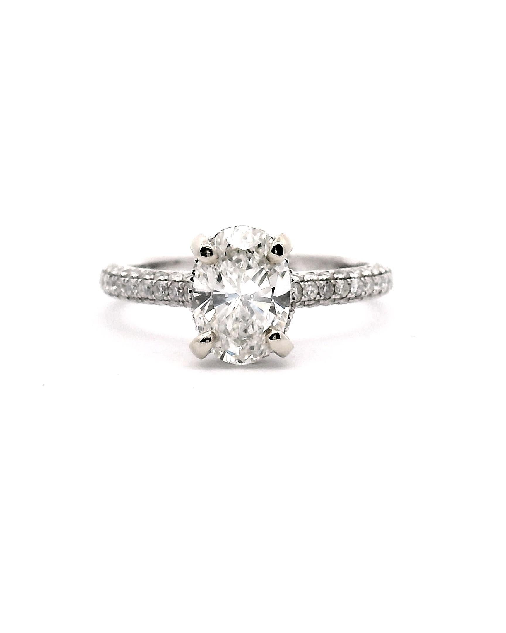 Lady's white gold engagement ring with oval faceted diamond with a diamond halo and paveed set diamond shank.

Center oval diamond 1.27ct. 

Clarity grade is VS1

Color grade is H-I 

94 Halo & Side round diamonds  approximately .94cttw.

14k white