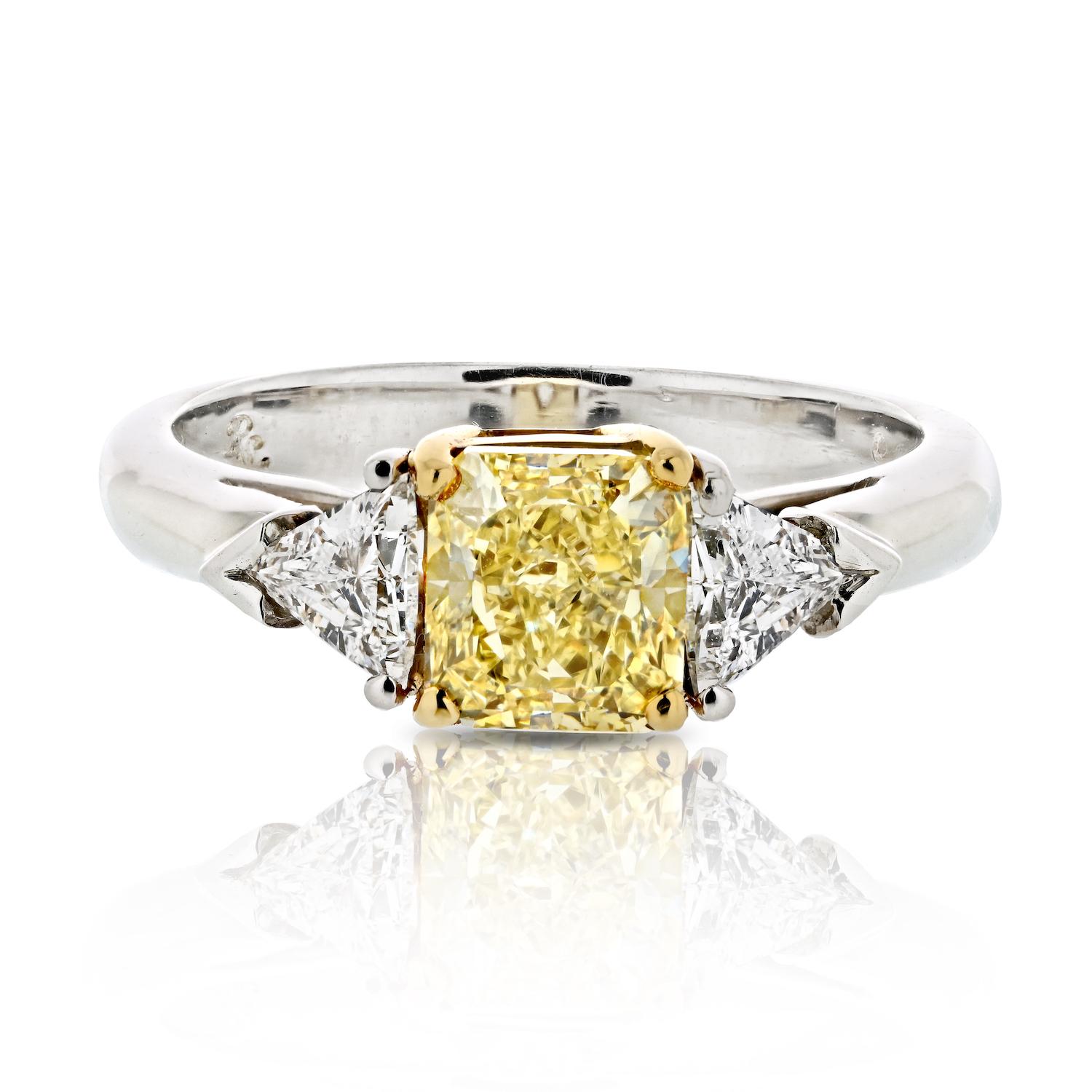 Celebrate the radiant journey of your love with this 1.27 carat Radiant Cut Fancy Yellow Trilliant Cut Three Stone Diamond Engagement Ring. The center stage belongs to a dazzling 1.27-carat radiant-cut diamond, a beacon of warmth and vibrancy in its