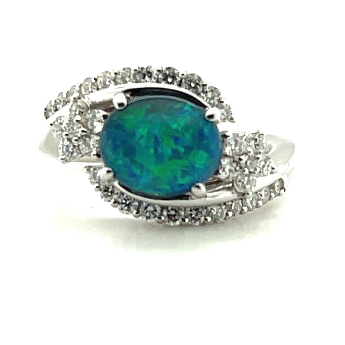 This gorgeous cocktail ring features a stunning 1.28 carat black opal set in platinum with brilliant white diamonds. The opal is a bright and lively gem with strong play-of-color that displays vibrant peacock blue and green flashes with a touch of