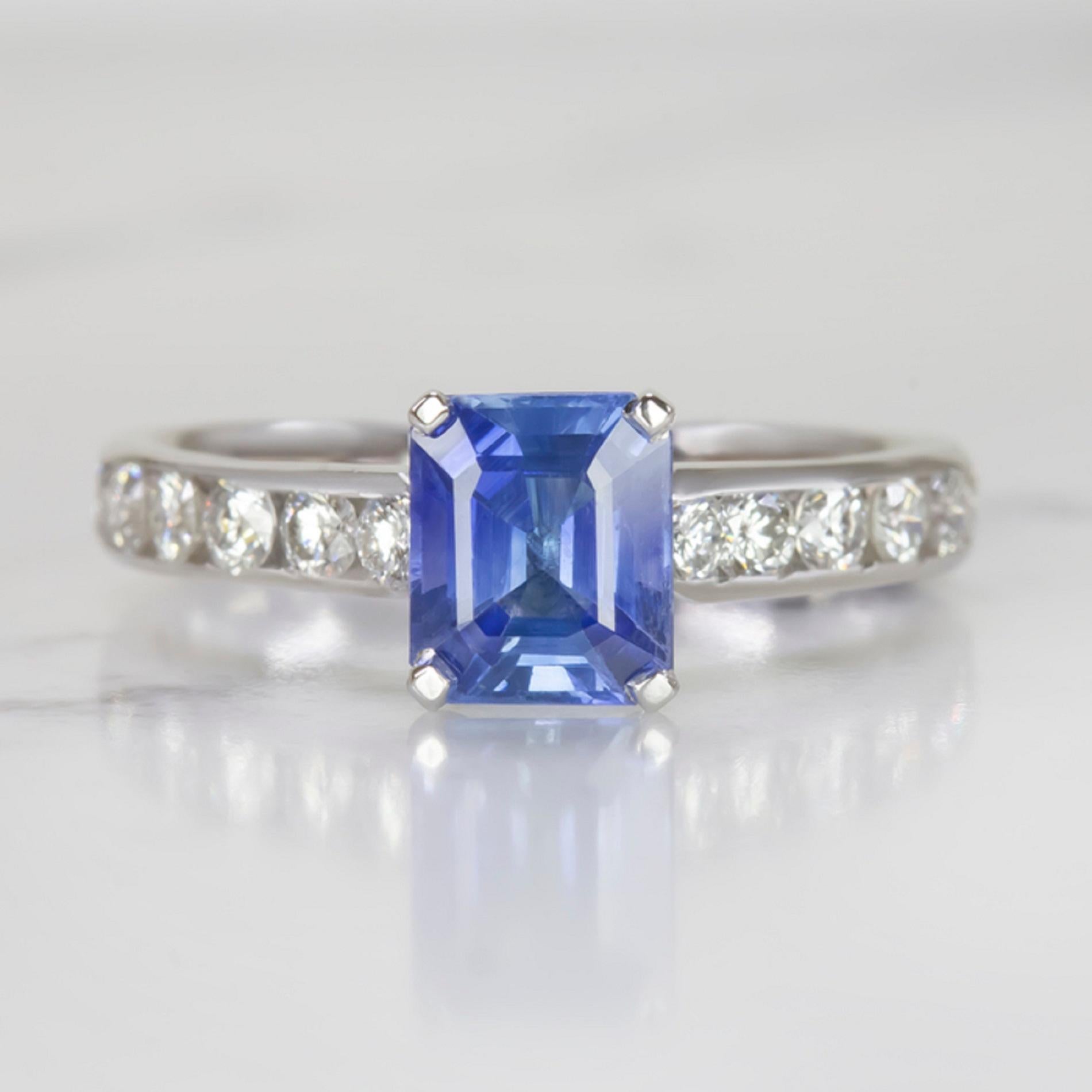  stunning sapphire and diamond ring is positively gleaming with eye catching sparkle! The 1.28 carat sapphire center has a beautiful cornflower blue hue and sparkles with gorgeous brilliance. The shoulders of the classic setting glitter with vibrant