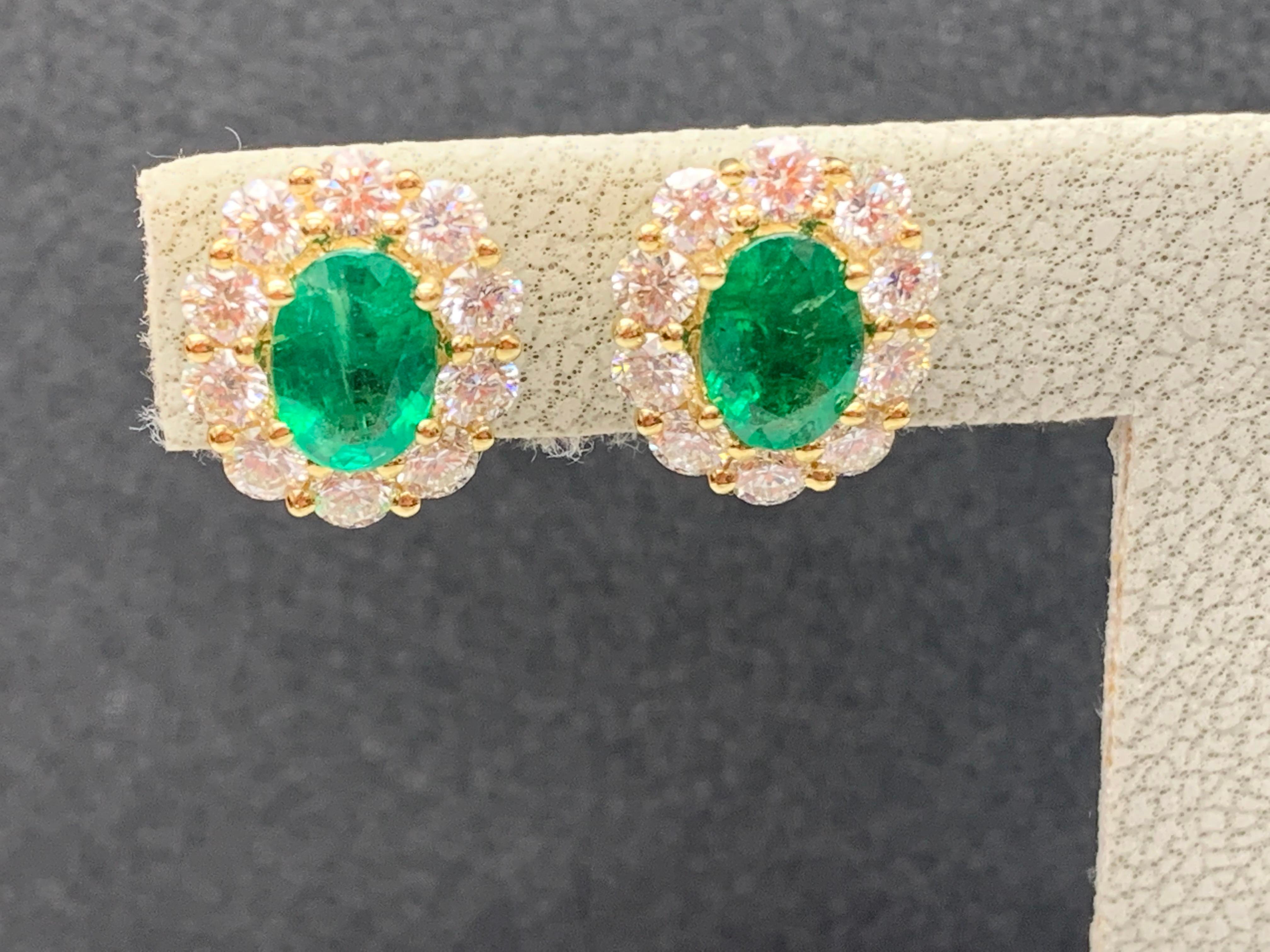A simple pair of stud earrings showcasing 1.28 carats of 2 oval cut lush green emeralds, surrounded by a single row of 20 round brilliant diamonds weighing 1.35 carats. Made in 18-karat white gold.