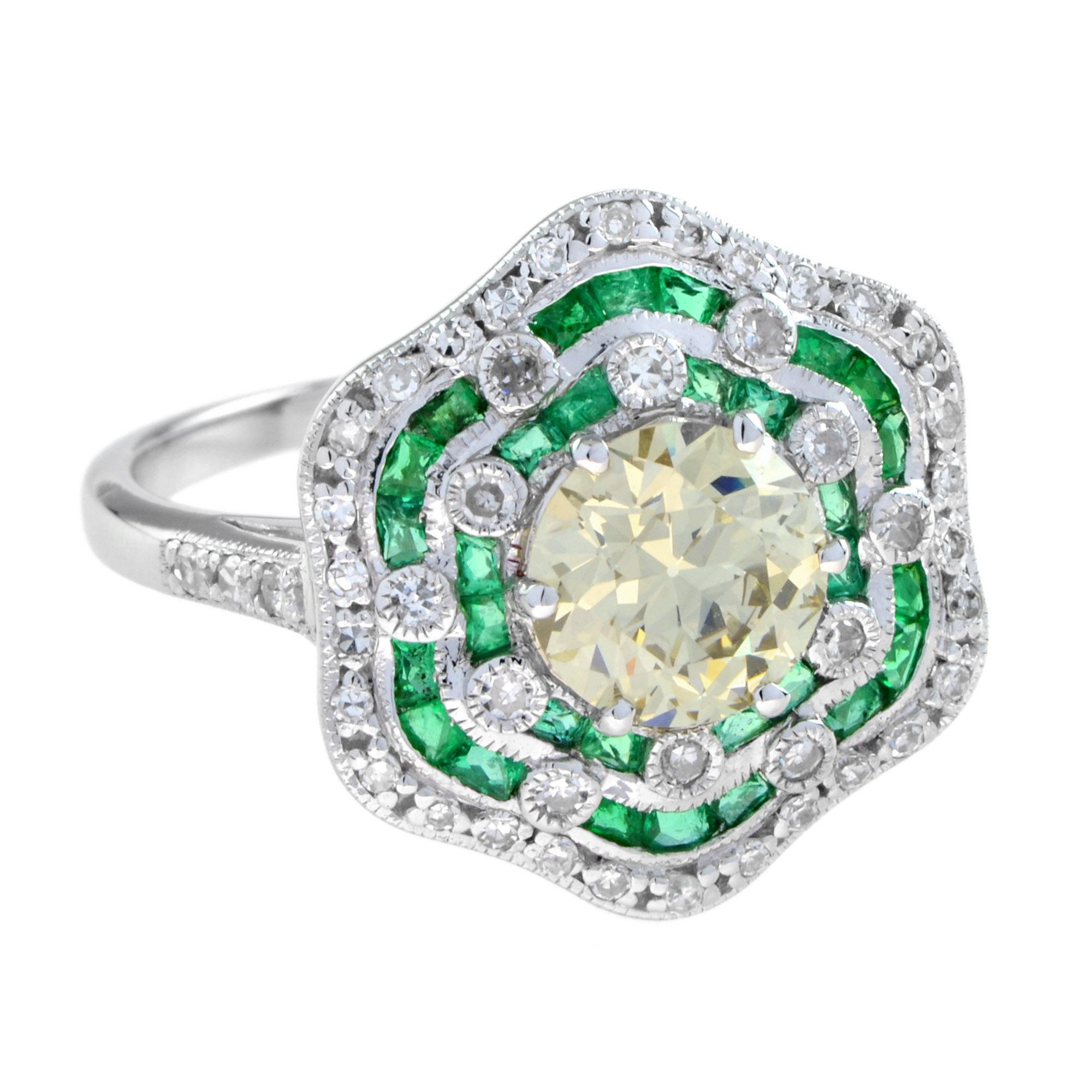 Ein eleganter, vom Art Deco inspirierter Verlobungsring ist mit einem antiken gelben Diamanten im Minenschliff besetzt und mit Diamanten und Millgrain verziert. Der Diamant ist von leuchtend grünen Smaragden umgeben, die mit runden Diamanten im