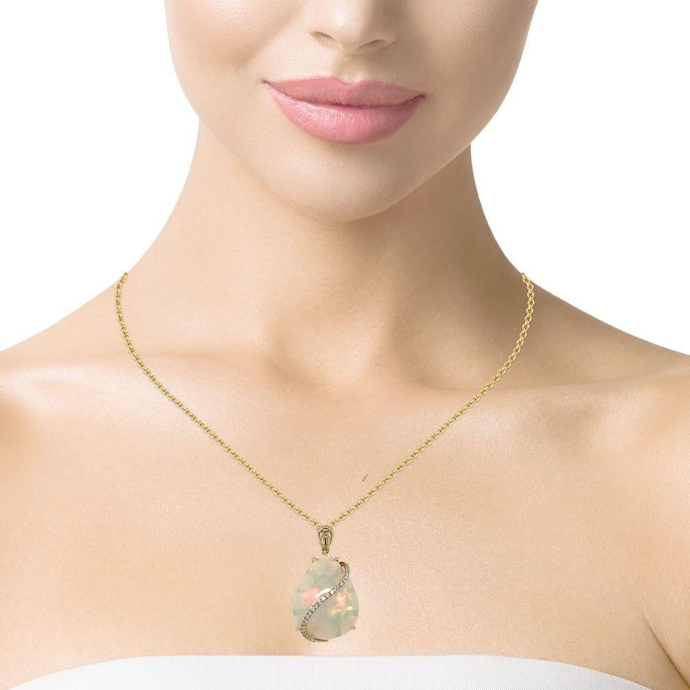 This stunning statement pendant has a 12.58 ct pear shape Ethiopian Opal with a swirl of 27 brilliant cut round diamonds elegantly crossing the stone. The Opal is 4 prong set in 14K yellow gold. This beautiful necklace will be the talk of your