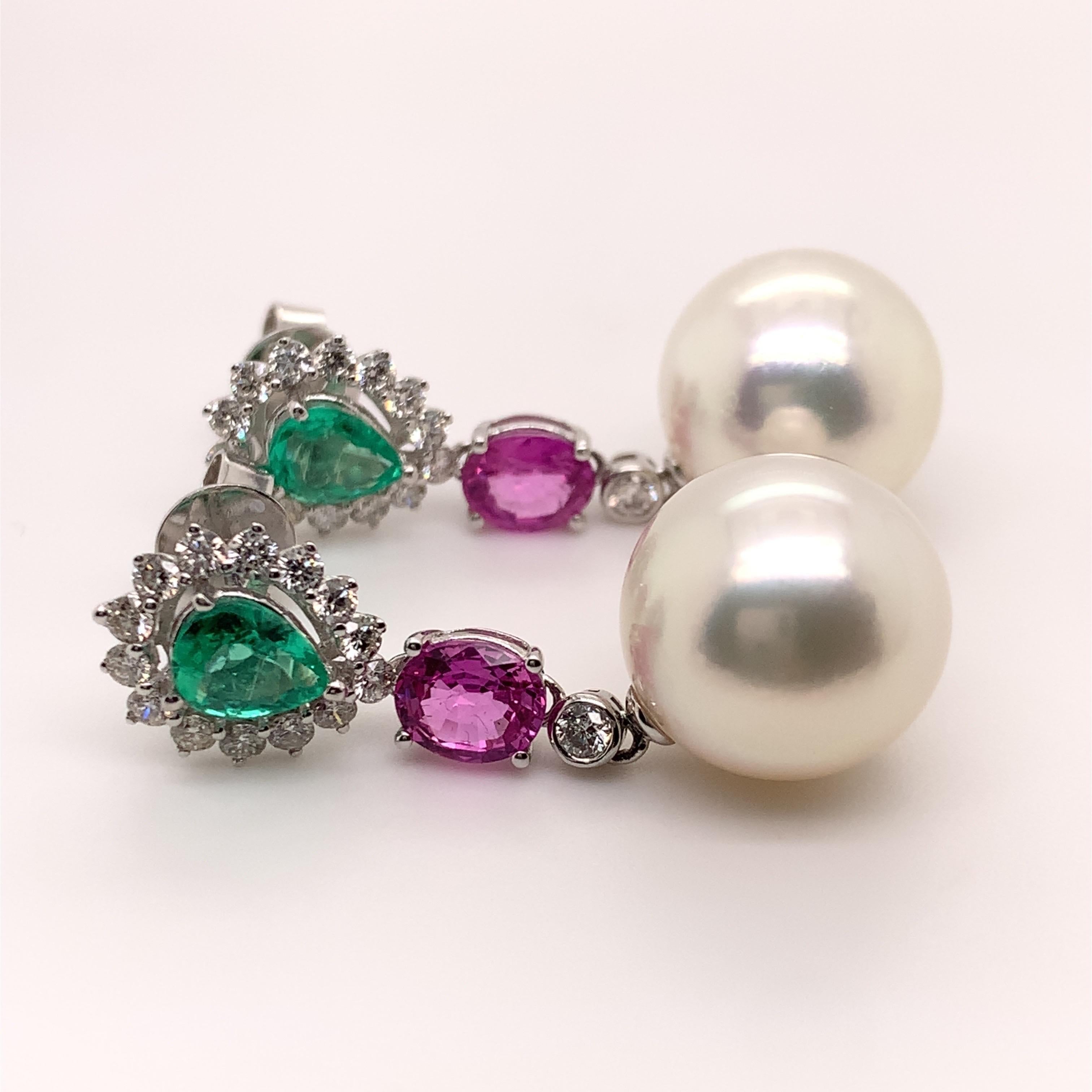 Stunning South Sea White Pearl Earrings. High brilliance, 12.8mm round white with silver overtone South Sea pearls accented with pear faceted lively green matching emerald surrounded with round brilliant cut diamonds and oval faceted lively matching