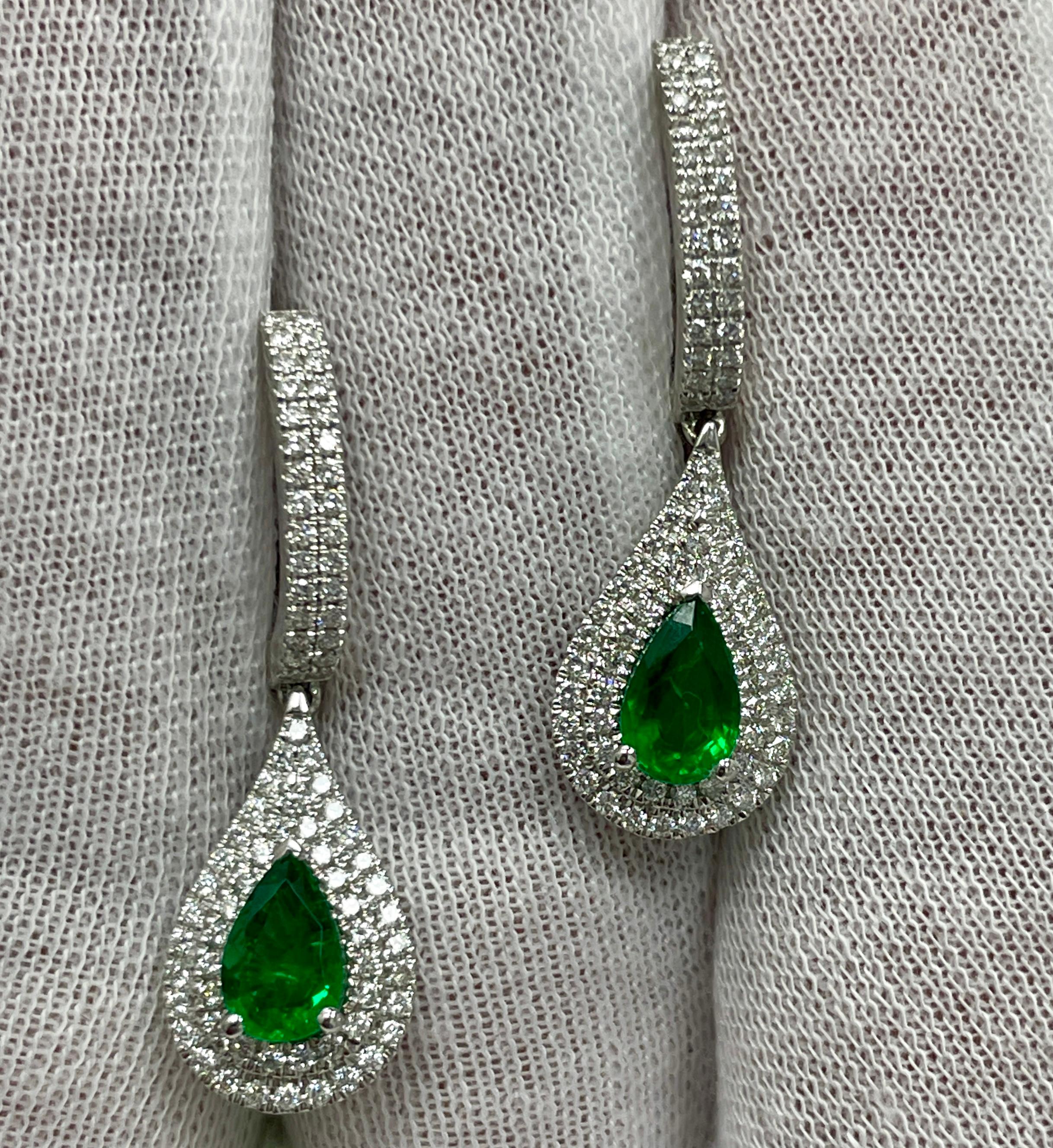 These dangling 18K white gold earrings carry .73Ct of brilliant white diamonds and 1.29Ct of stunning matching pear shape emeralds