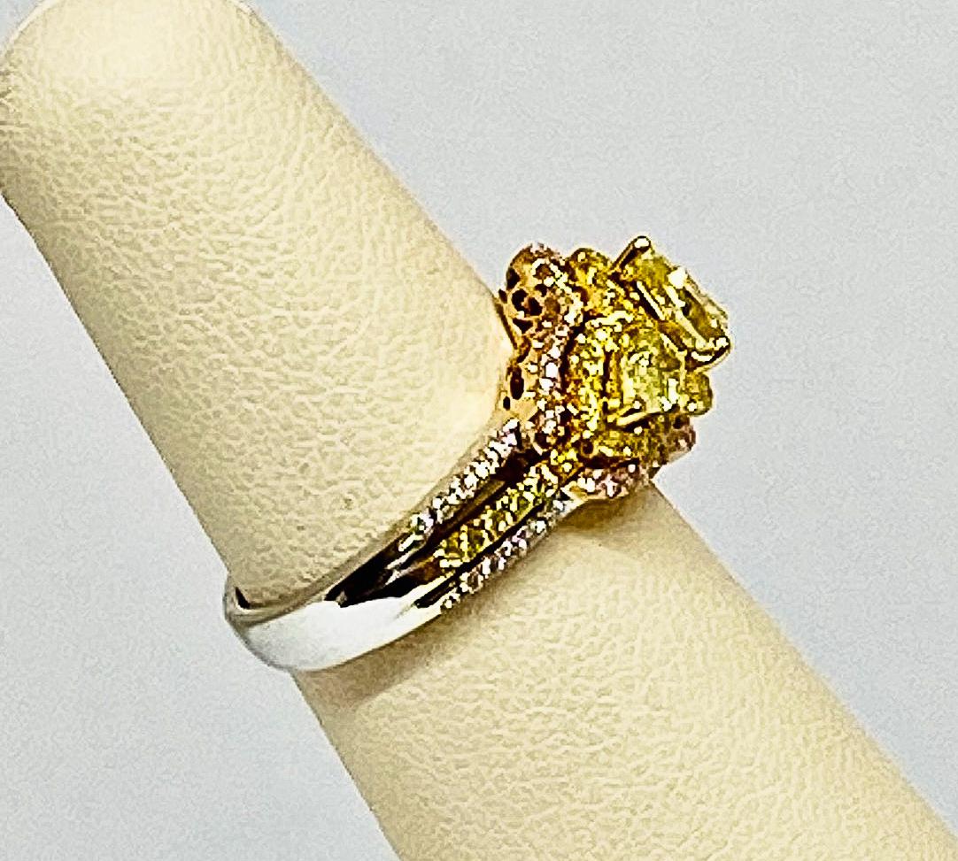 Beautiful three stone ring featuring three pear shaped prong set fancy yellow diamonds all surrounded by a hallow of round yellow diamonds all weighing a total of 1.29 carats set in 18KT yellow gold and is further accentuated by an outer halo of