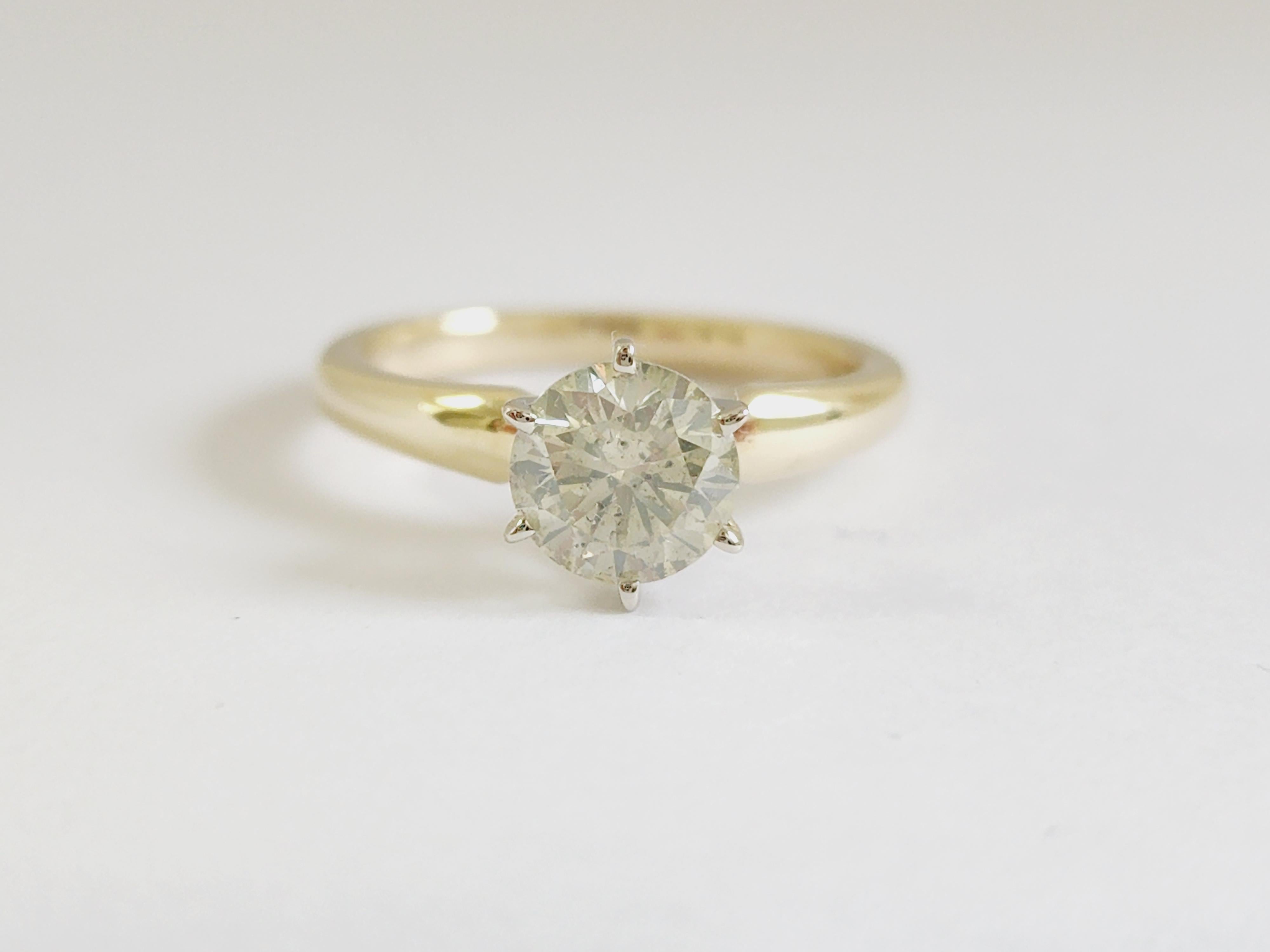 Diamant rond GIA de 1,29 carats serti sur une bague solitaire à 6 griffes en or jaune 14 carats. 
Couleur O-P, Clarté I2
Taille de l'anneau 7 