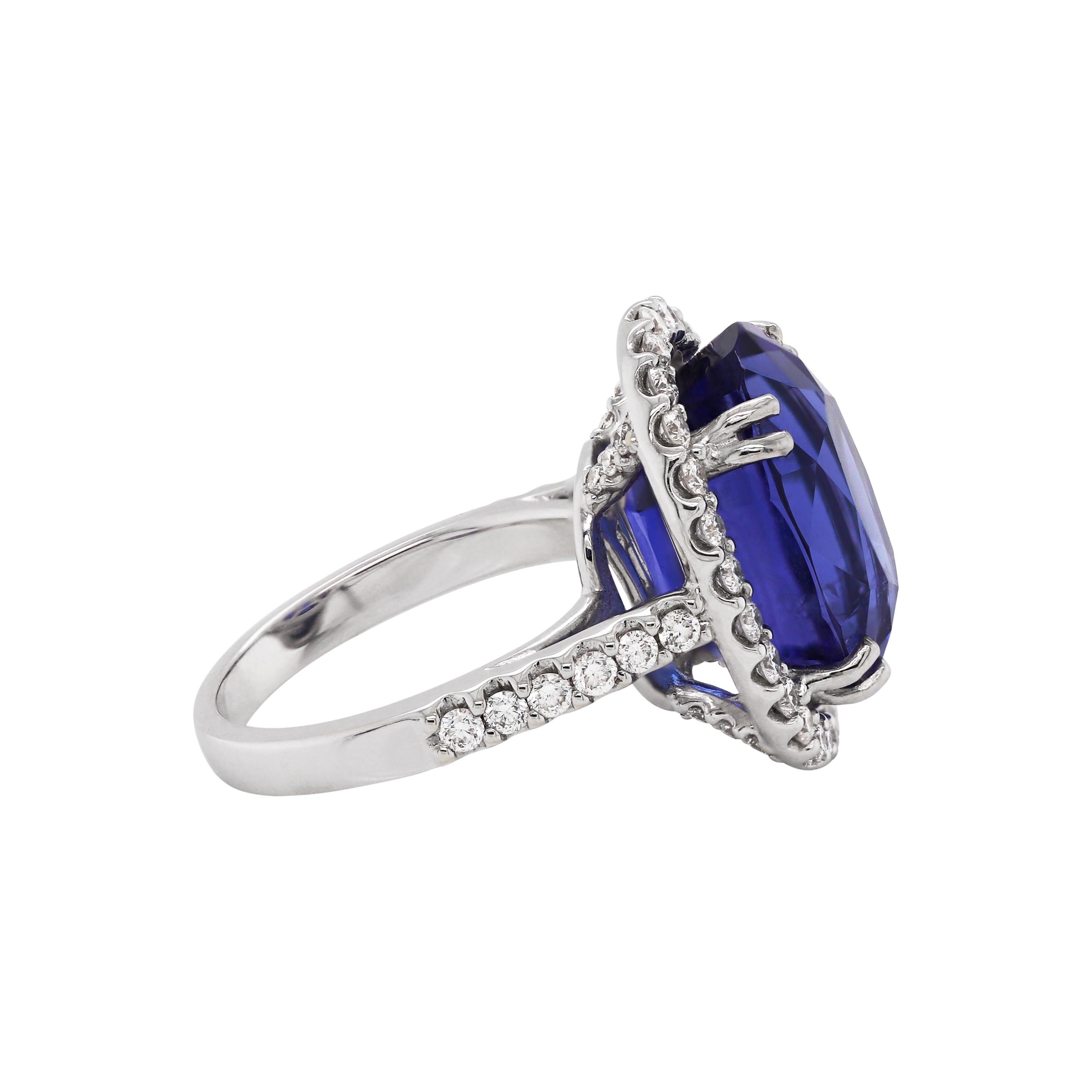 Beautiful cocktail ring set with an oval shaped tanzanite weighing a total of 12.90 carats in a four double claw open back setting. The tanzanite is mounted in the centre of a halo, claw set with fine quality round brilliant cut diamonds. The shank